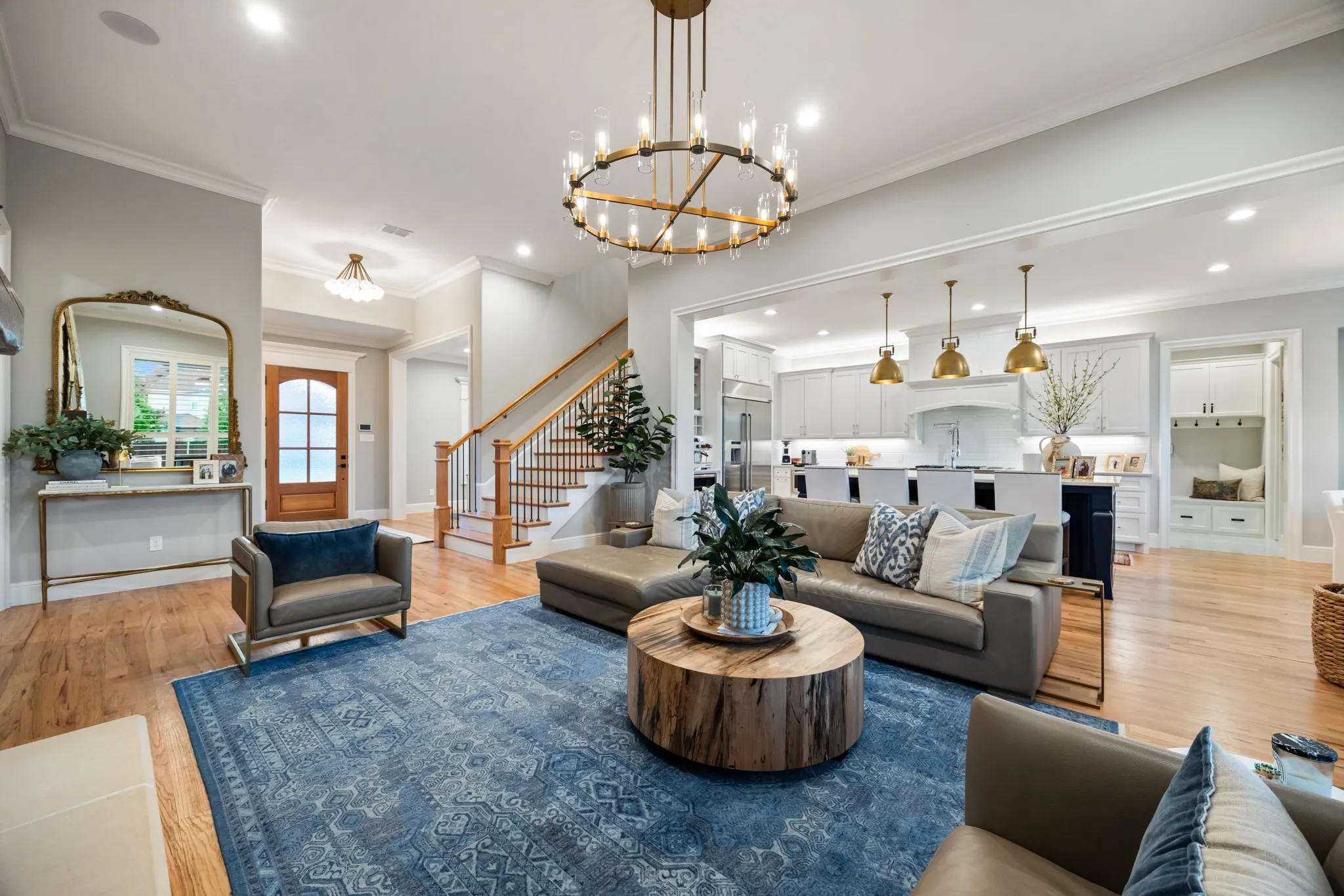Open living and kitchen under a tall ceilings with Restoration Hardware lighting. Hardwood throughout, and the natural gathering space of the home.
