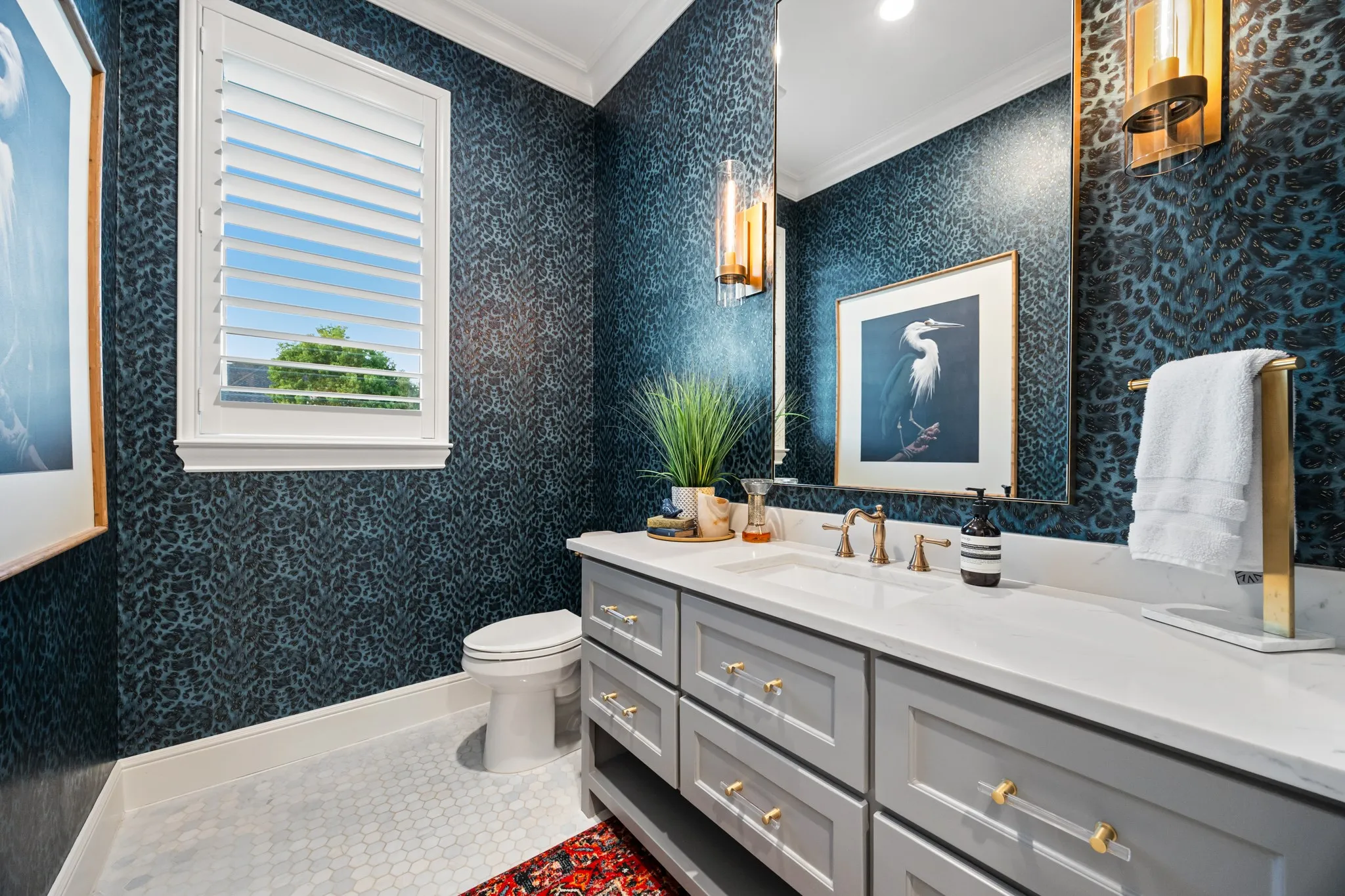 Guest bath detailed with moody designer wallpaper and a statement round mirror.