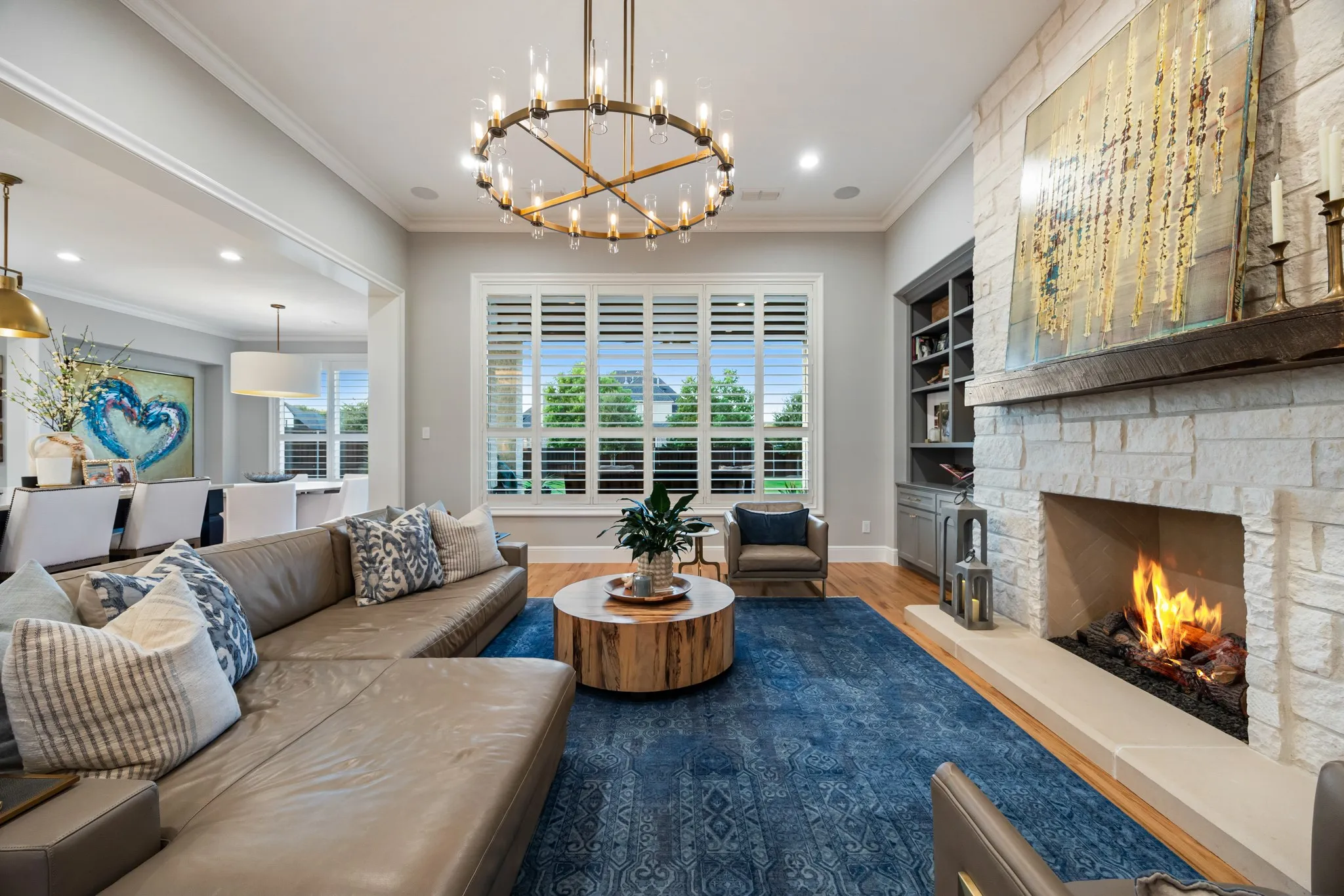 Fireplace framed in floor-to-ceiling stone grounds the living room, wrapped in oversized windows.