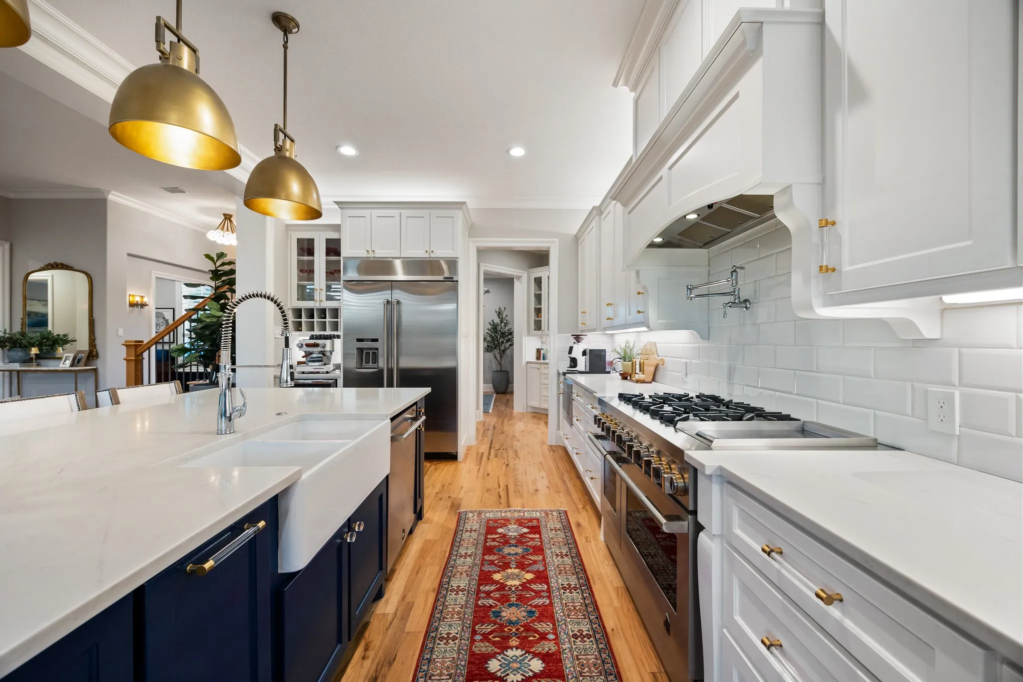 Deep navy cabinetry and gold pendant lighting add warmth to this open-concept kitchen.