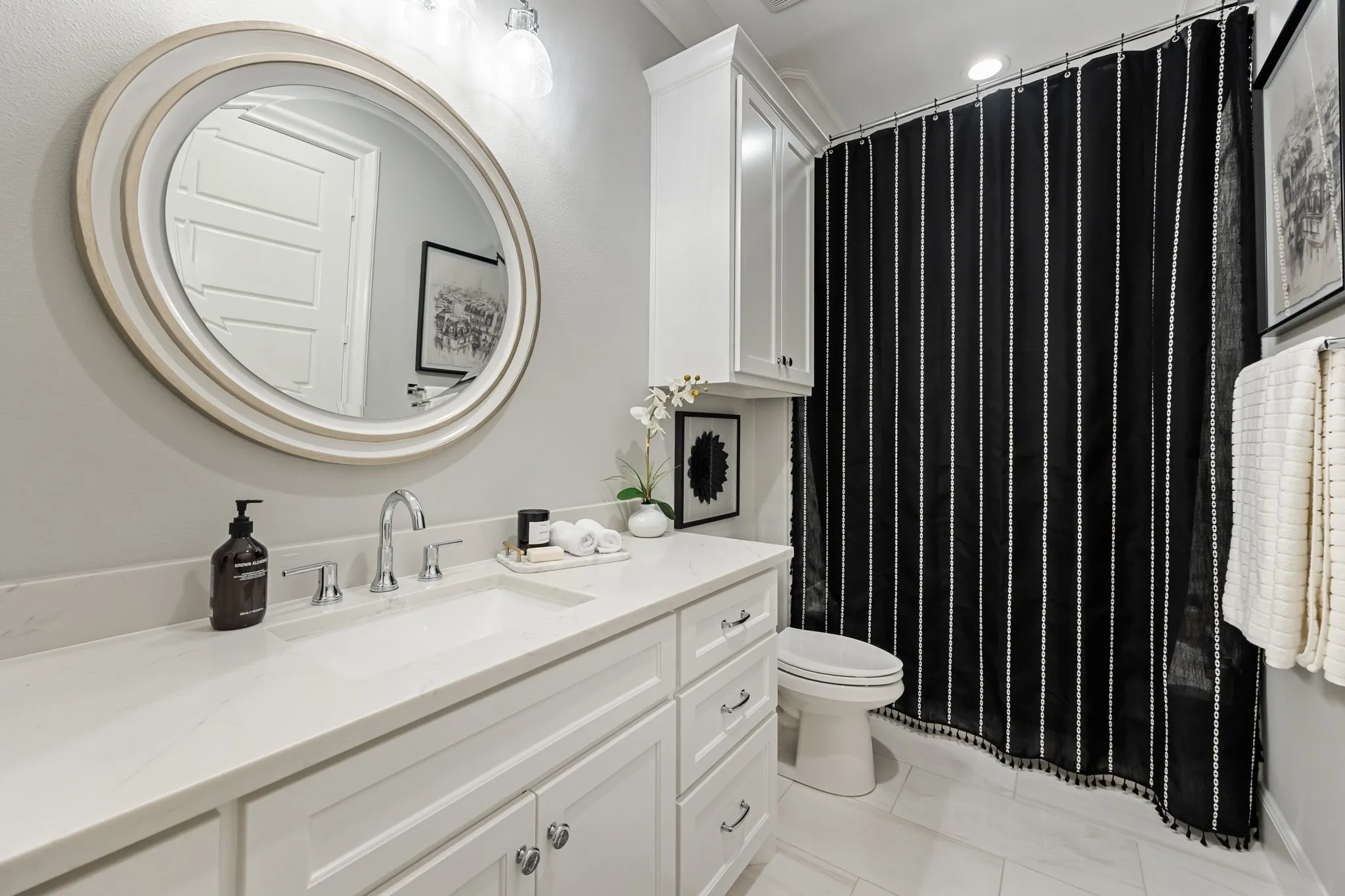 Clean, bright en-suite bath with a round mirror