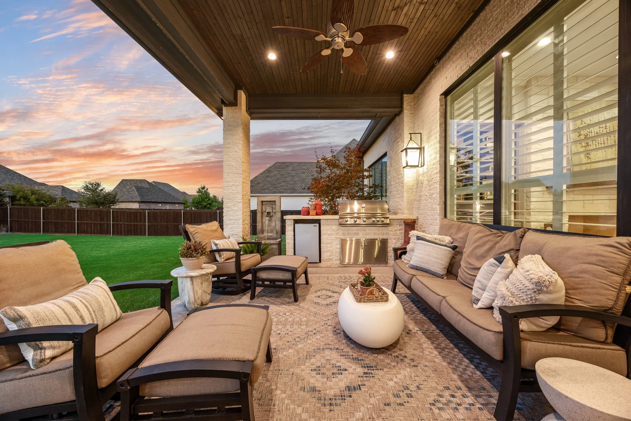 Covered patio furnished for relaxing evenings, overlooking the spacious backyard.