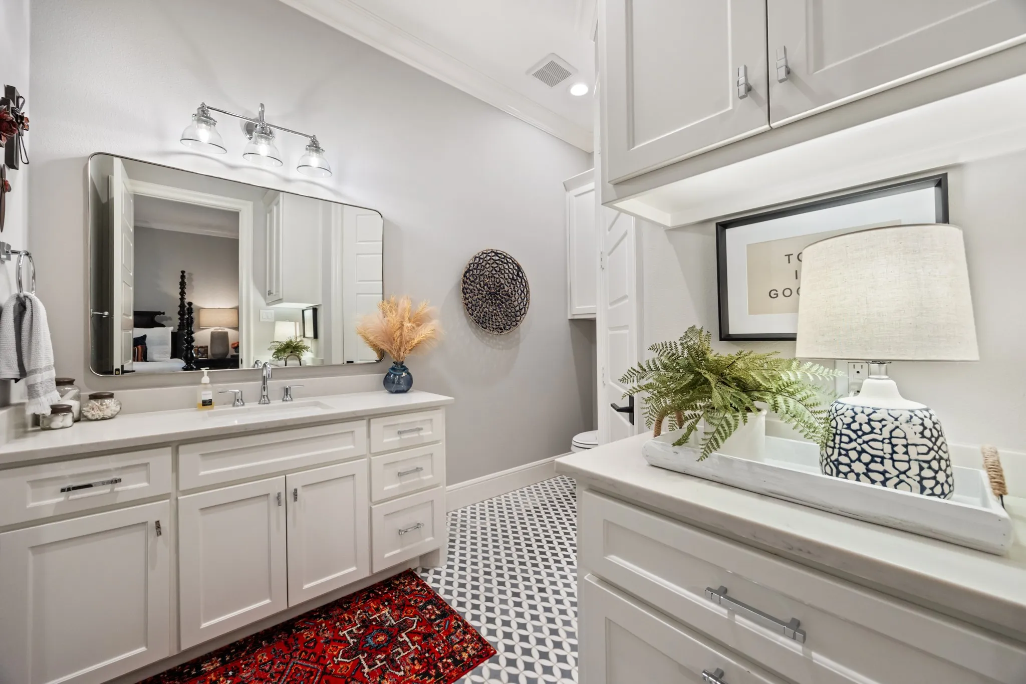 Crisp white cabinetry and a large mirror keep this en-suite bath bright and airy.