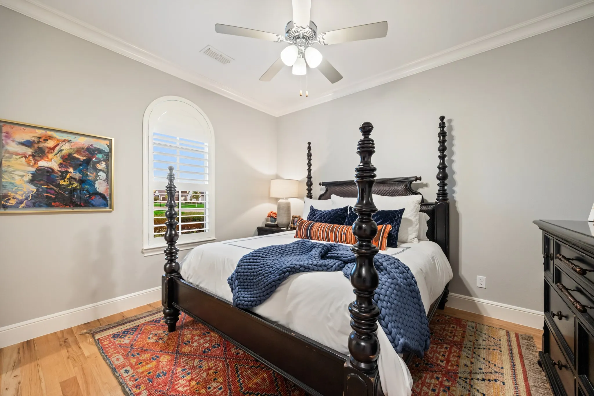Downstairs secondary bedroom framed by an arched window, with room for a statement bed.