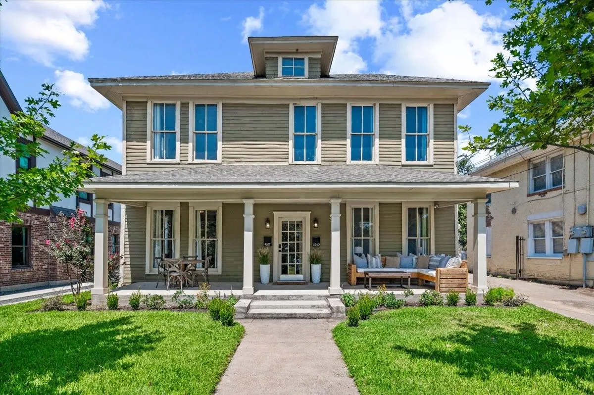 Two-story residence featuring a broad front porch, multiple windows, a dormer, and a well-maintained lawn