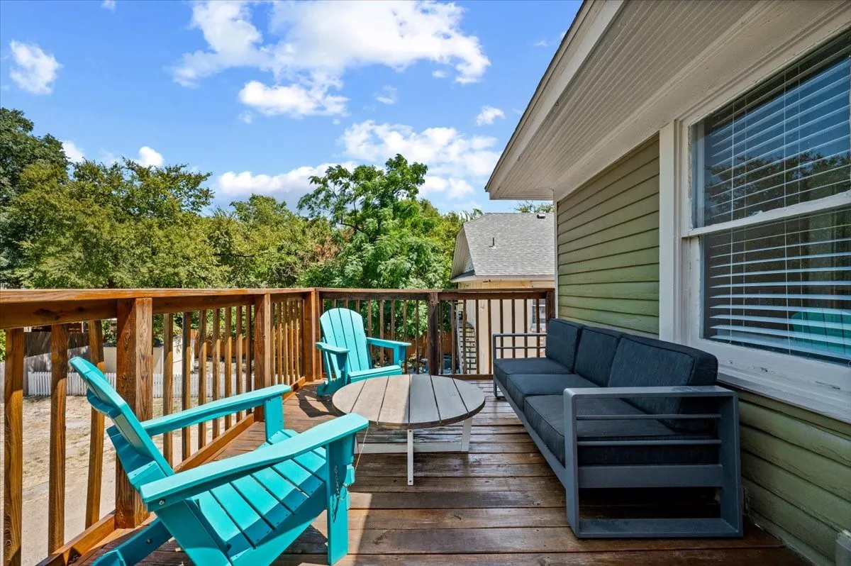 Spacious outdoor deck with wood-finish flooring, wood railing, and an exterior wall with horizontal siding