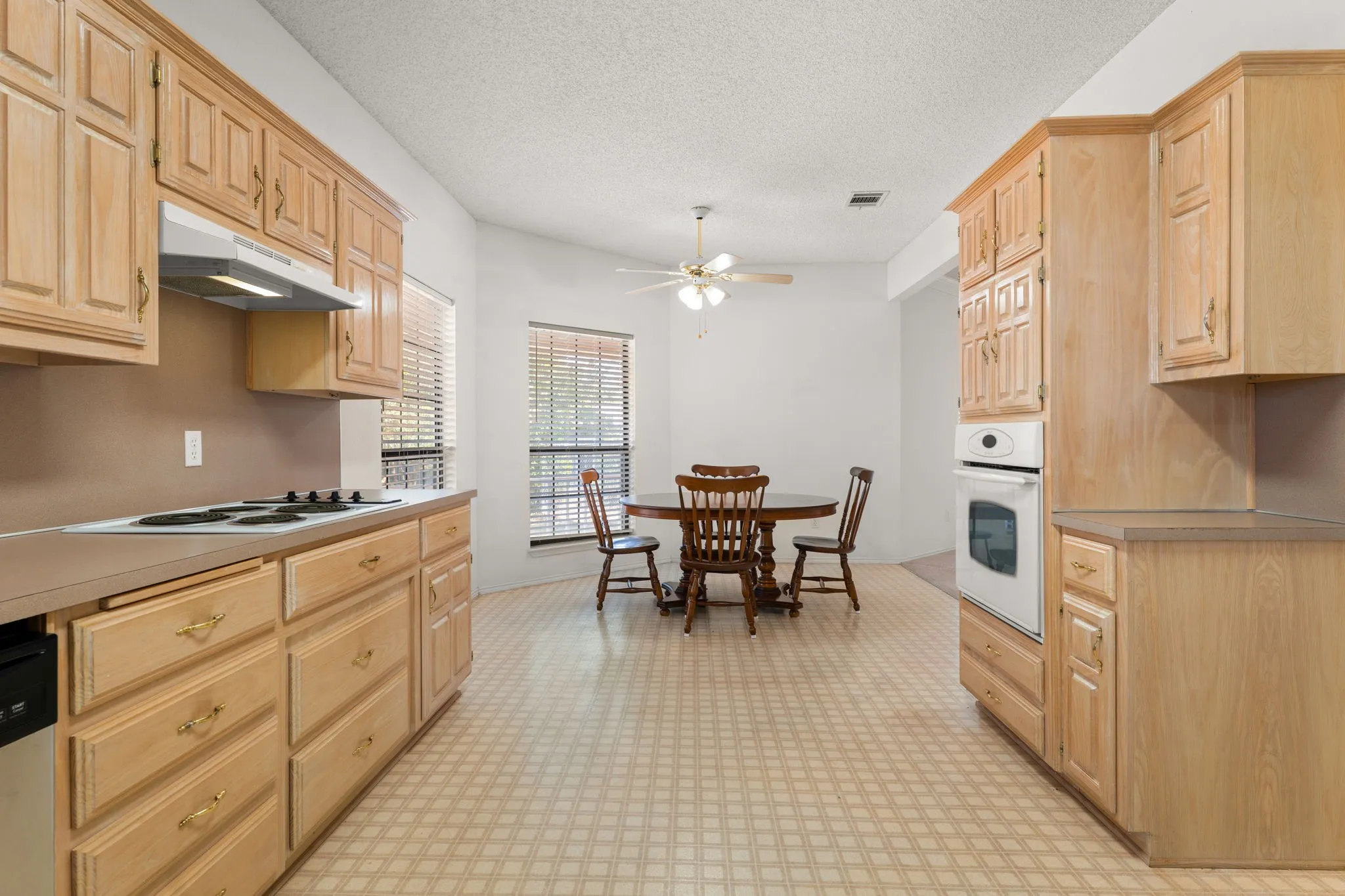 Kitchen with wood-finish cabinetry, built-in wall oven, and cooktop