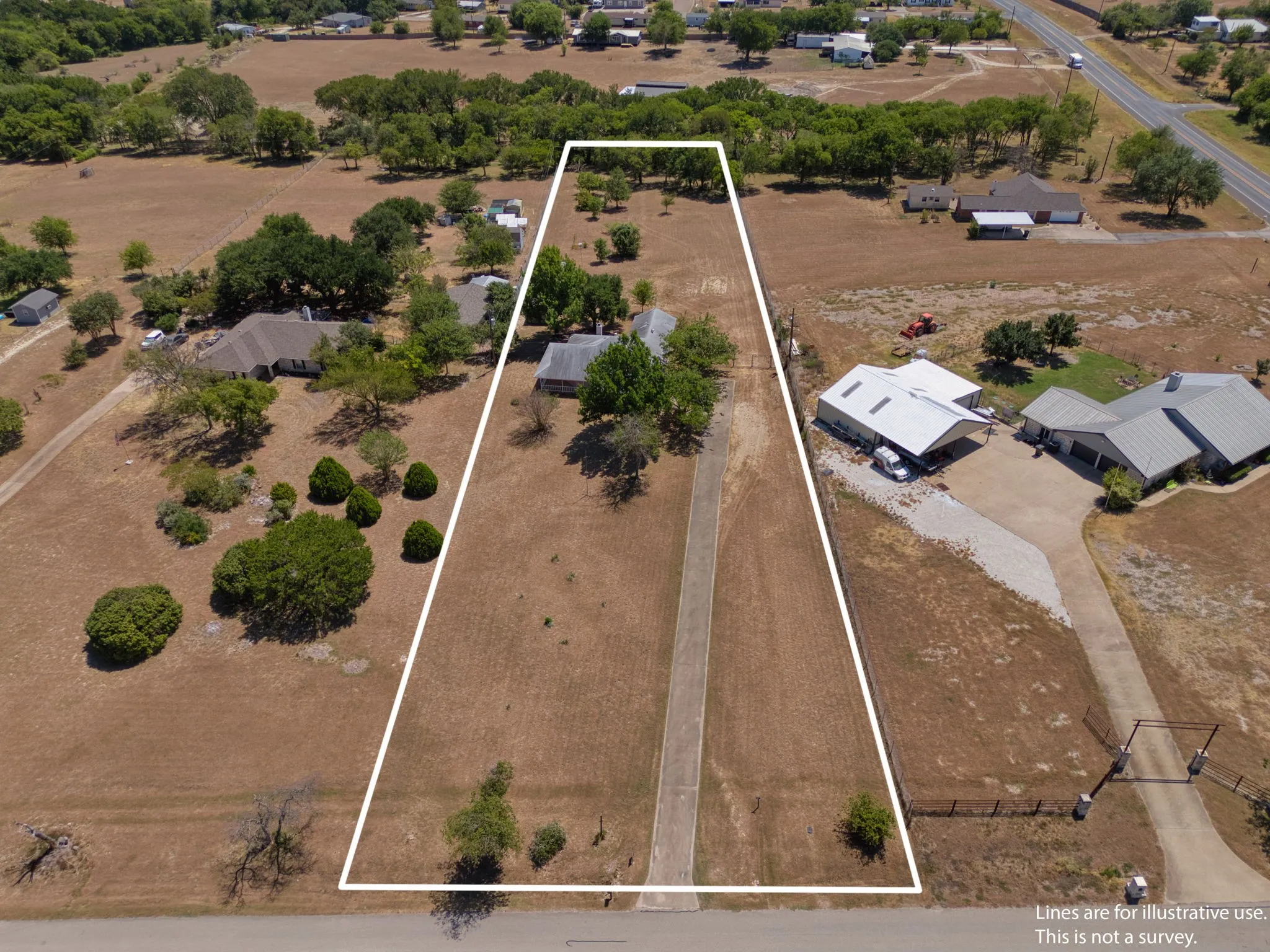 Expansive land parcel featuring a paved driveway, mature trees, and natural landscaping