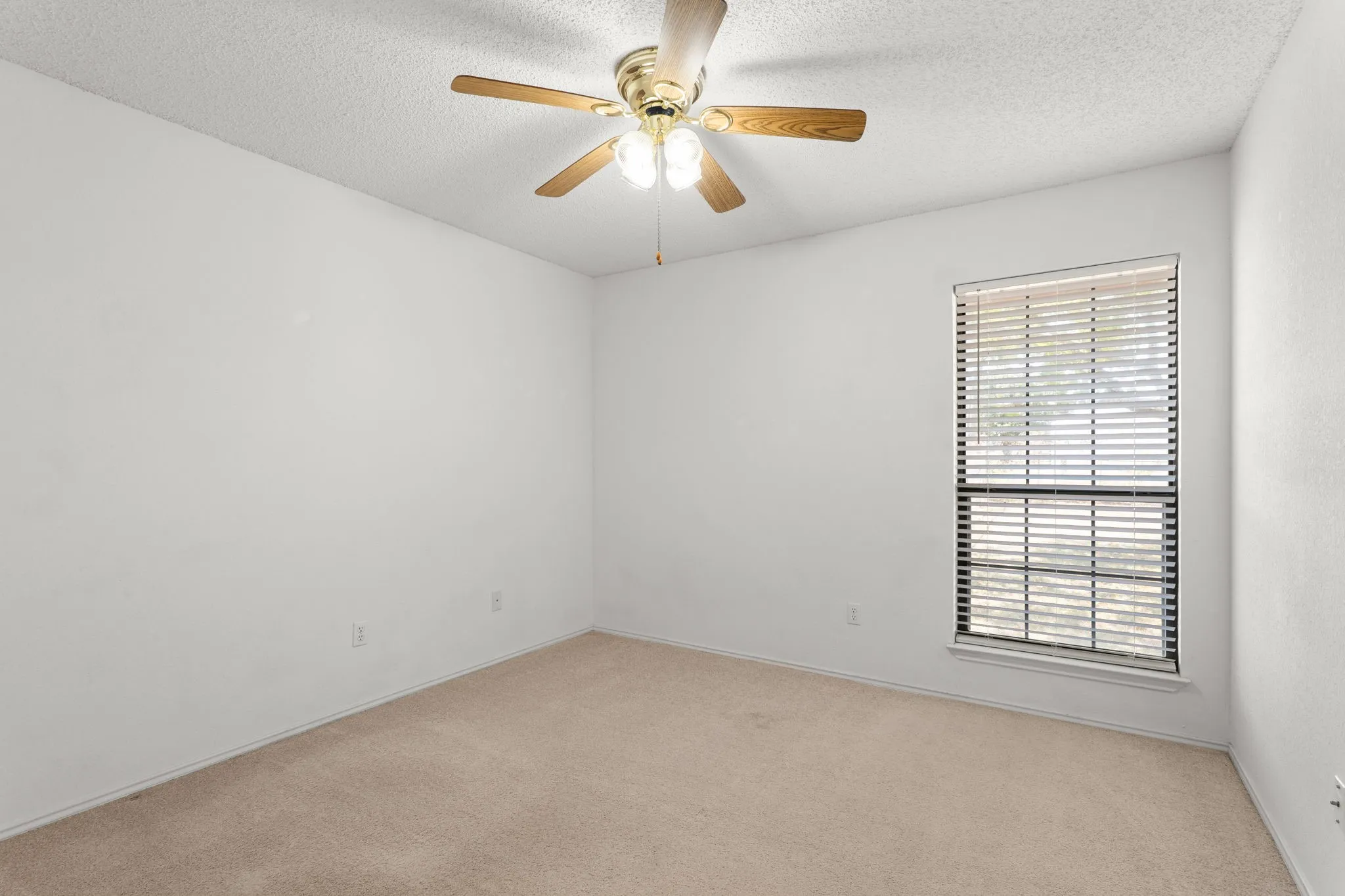 Recessed window with blinds, overhead ceiling fan with light fixture, and neutral carpeting