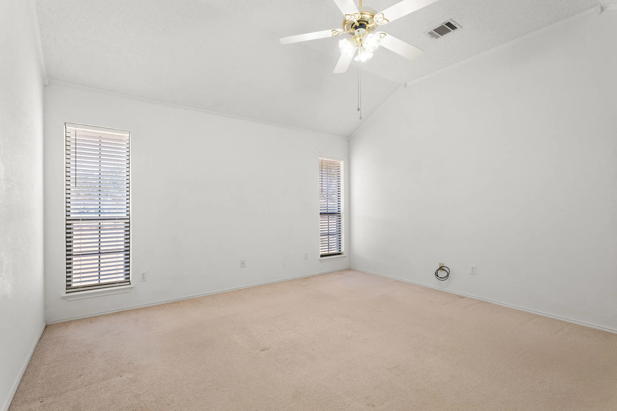 Vaulted ceiling, two windows with blinds, ceiling fan, carpeted flooring