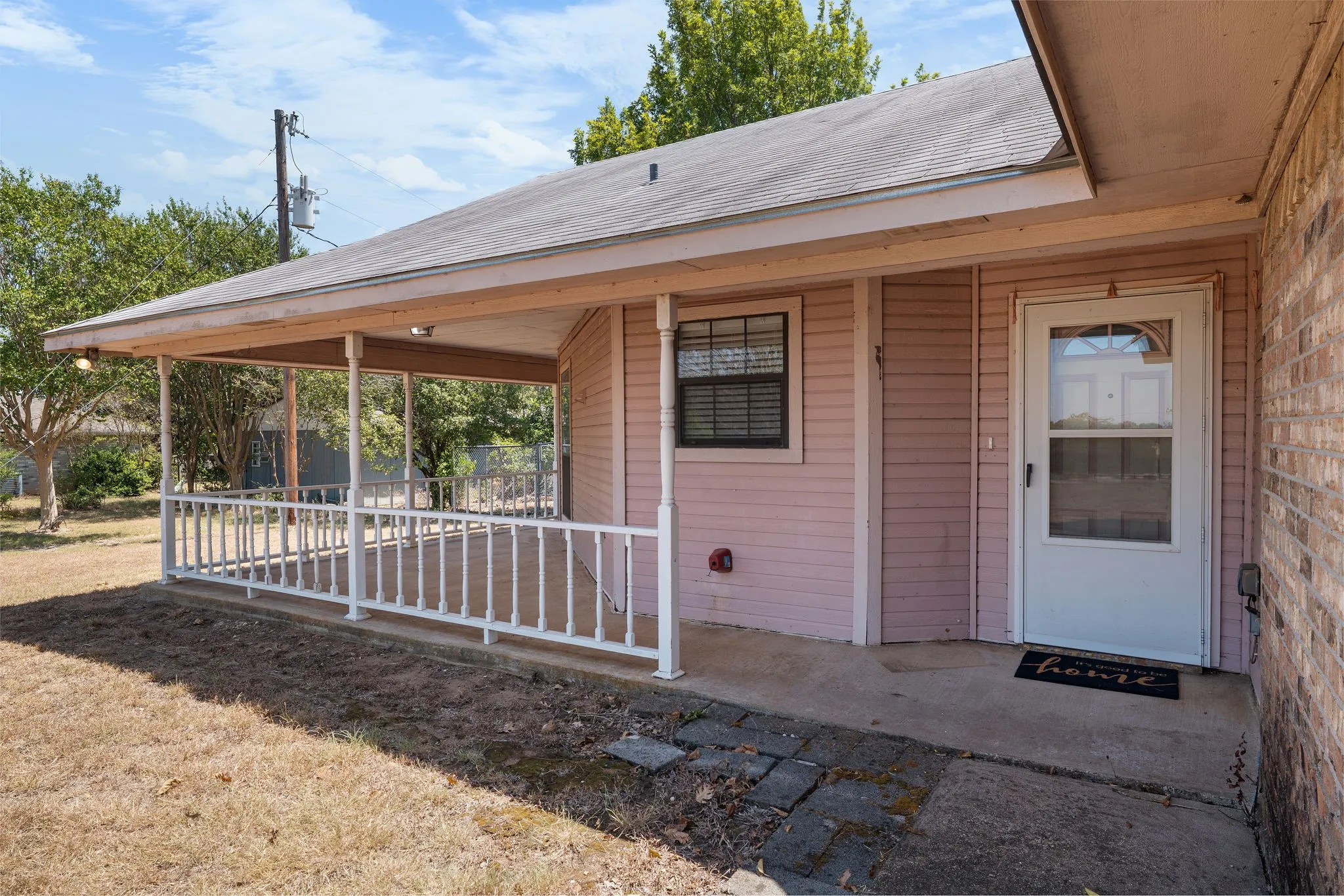 Covered front porch with white railings and an exterior door with a glass insert