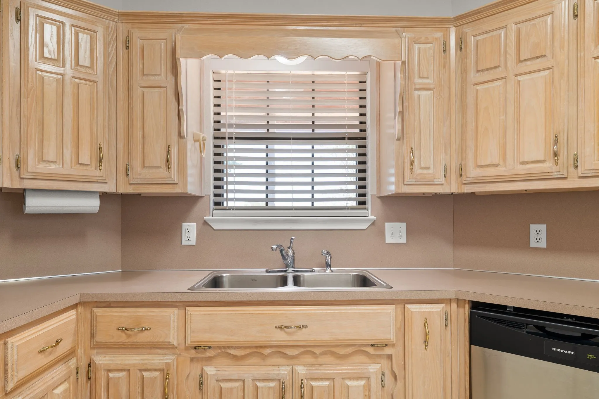 Kitchen featuring wood cabinetry, a double basin stainless steel sink, countertop space, and a built-in dishwasher
