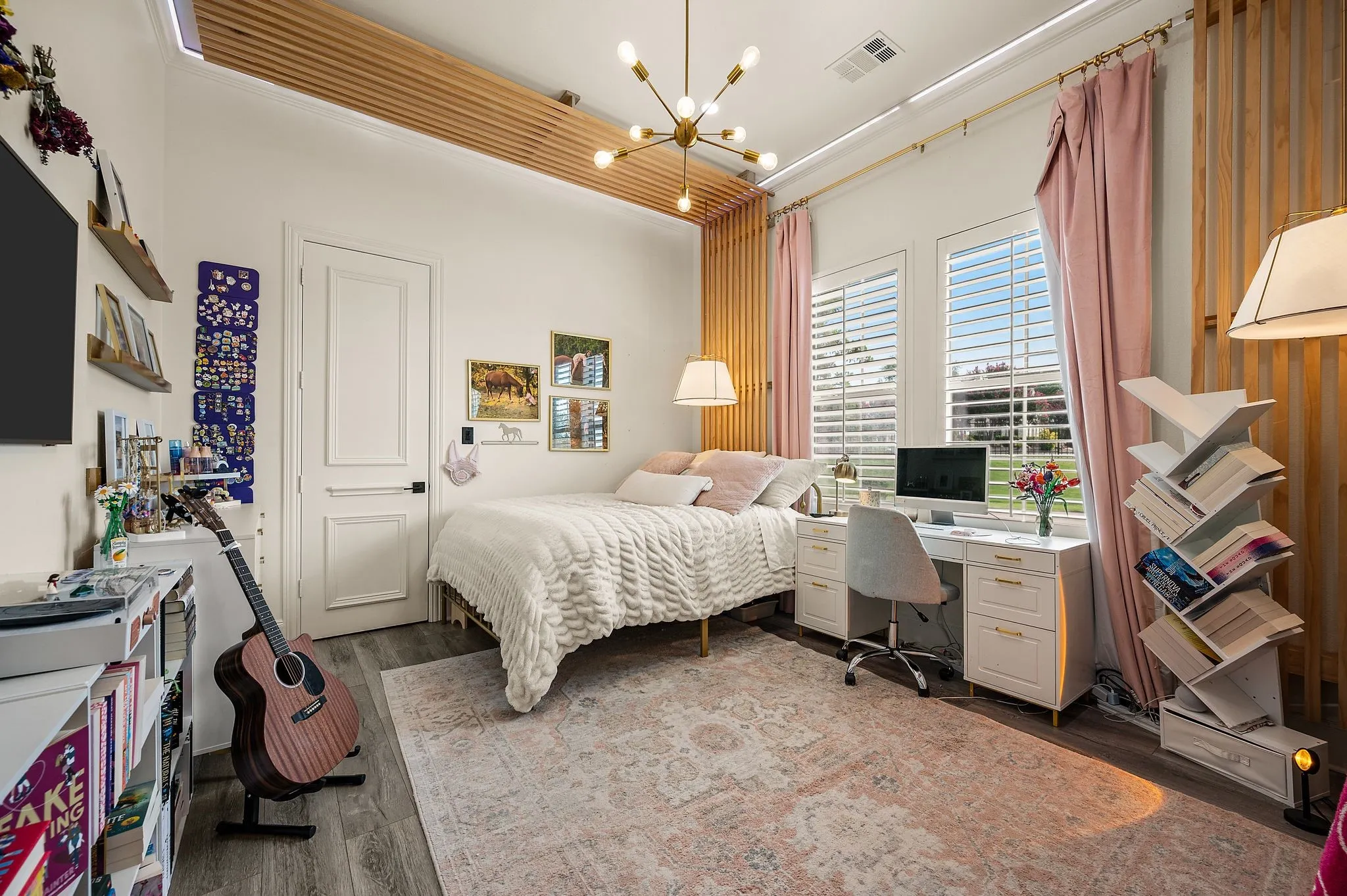 Bedroom featuring wood-finish flooring, two large windows with plantation shutters, a contemporary ceiling fixture, and decorative wood slat wall accents