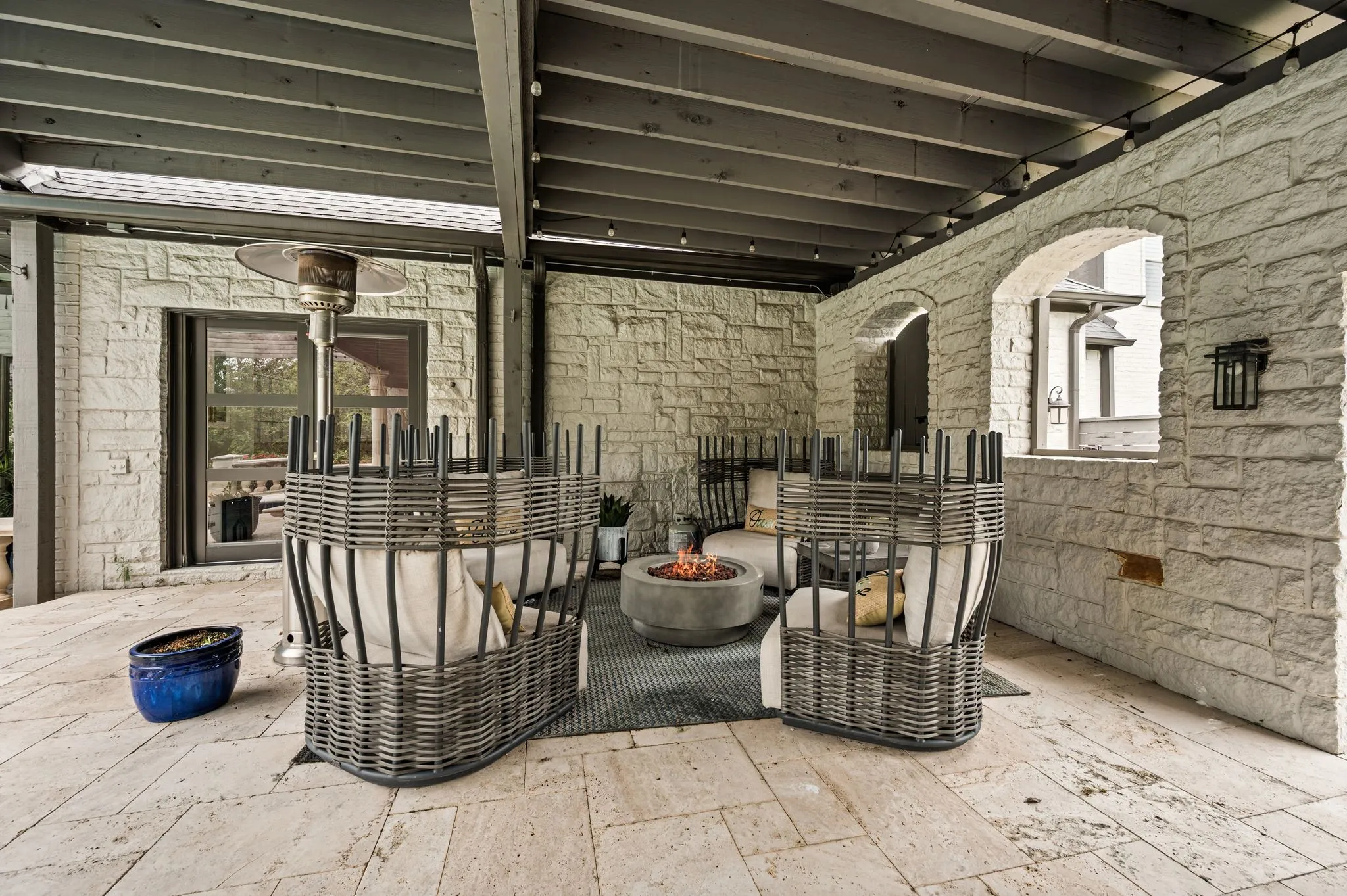 Covered outdoor patio featuring stone tile flooring, stone walls, and arched openings
