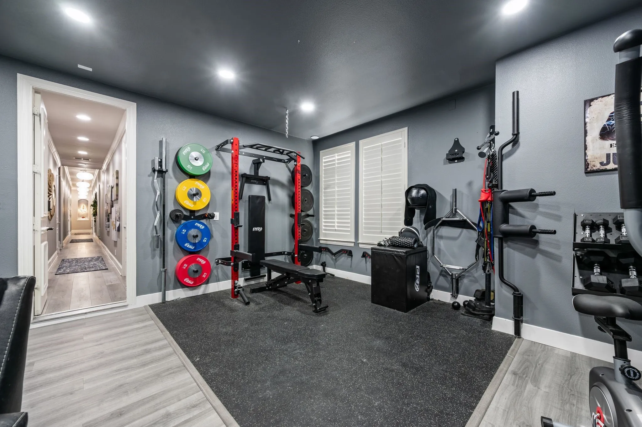 Dedicated fitness space featuring rubber flooring, recessed lighting, and wall-mounted plate storage