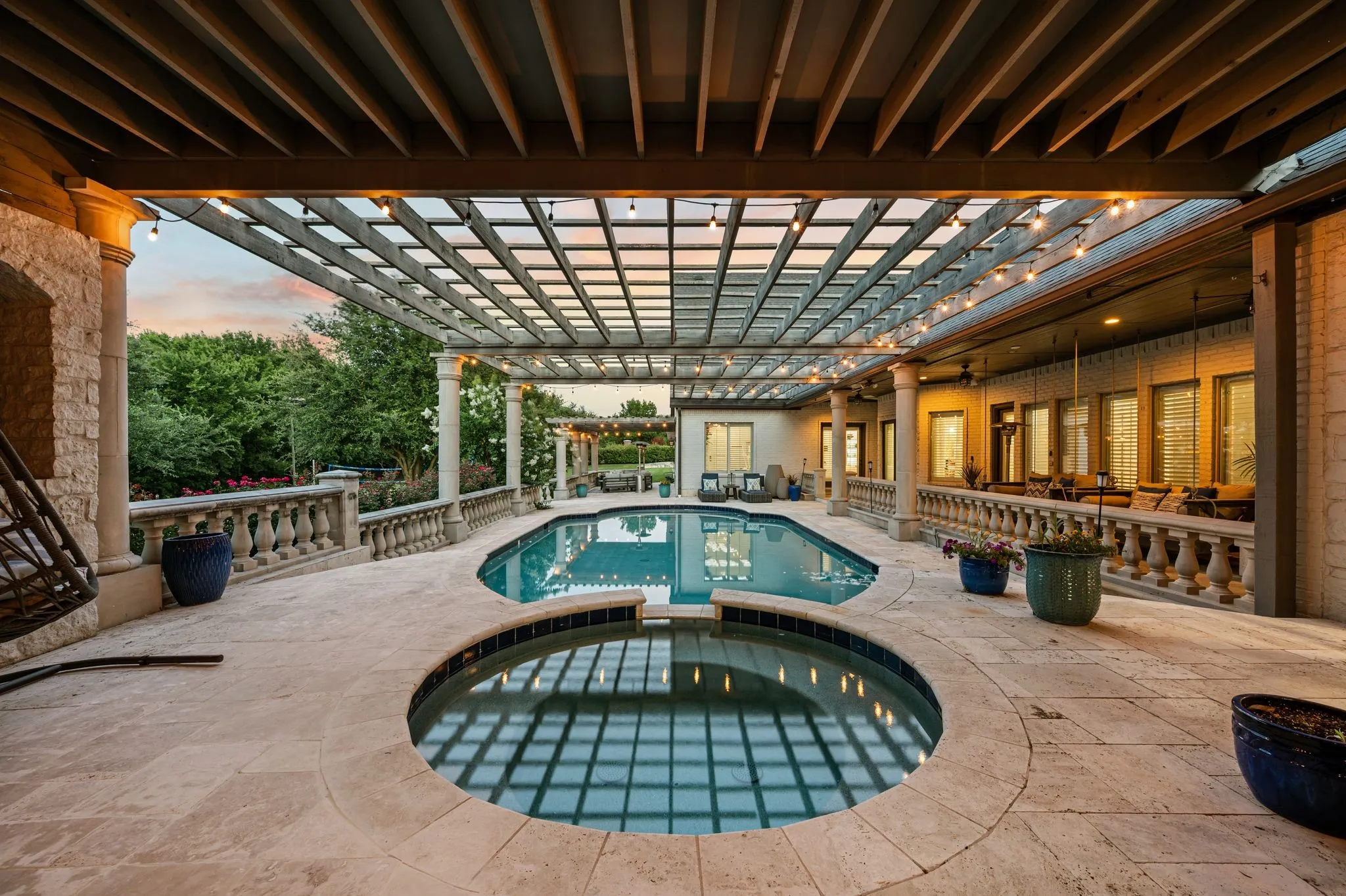 Expansive patio featuring a built-in pool and spa, stone balustrades, and a louvered pergola with integrated lighting