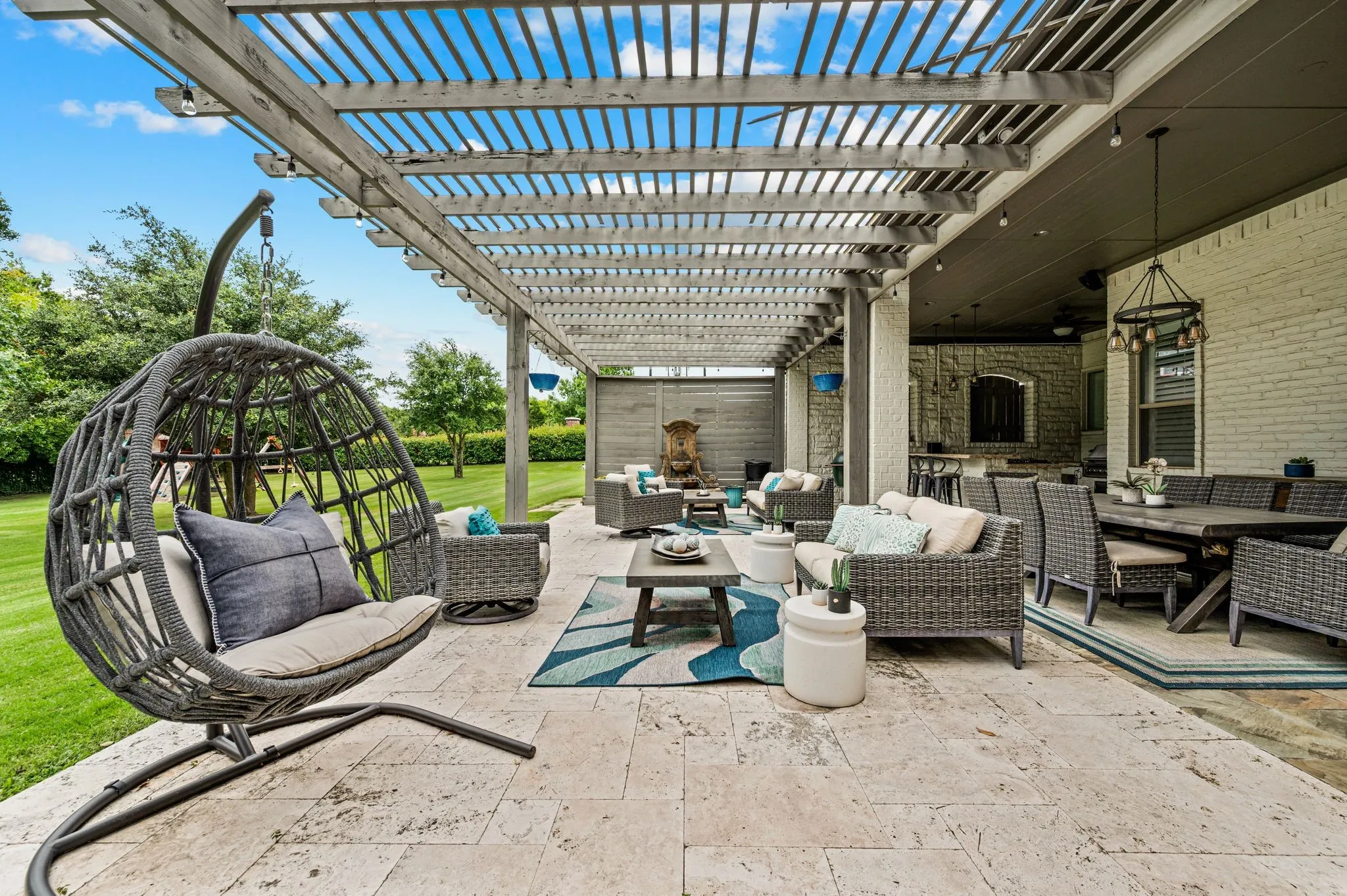 Expansive outdoor living area featuring a wood pergola and a stone tile patio