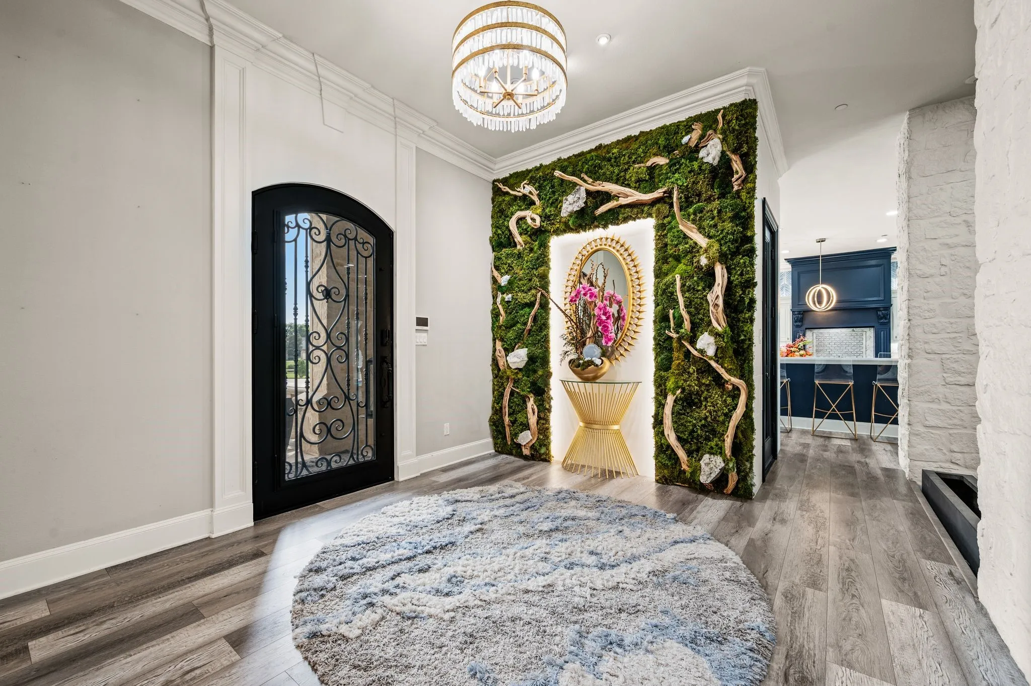 Grand entry featuring a custom wrought iron and glass arched door and moss wall