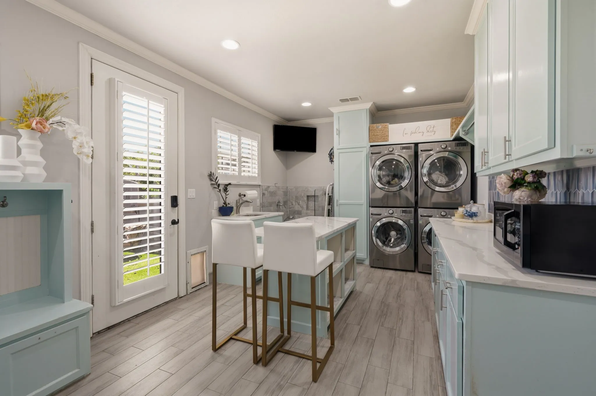 Utility room featuring PET WASH STATION, wood-finish flooring, light blue cabinetry, and a central island with a solid surface countertop