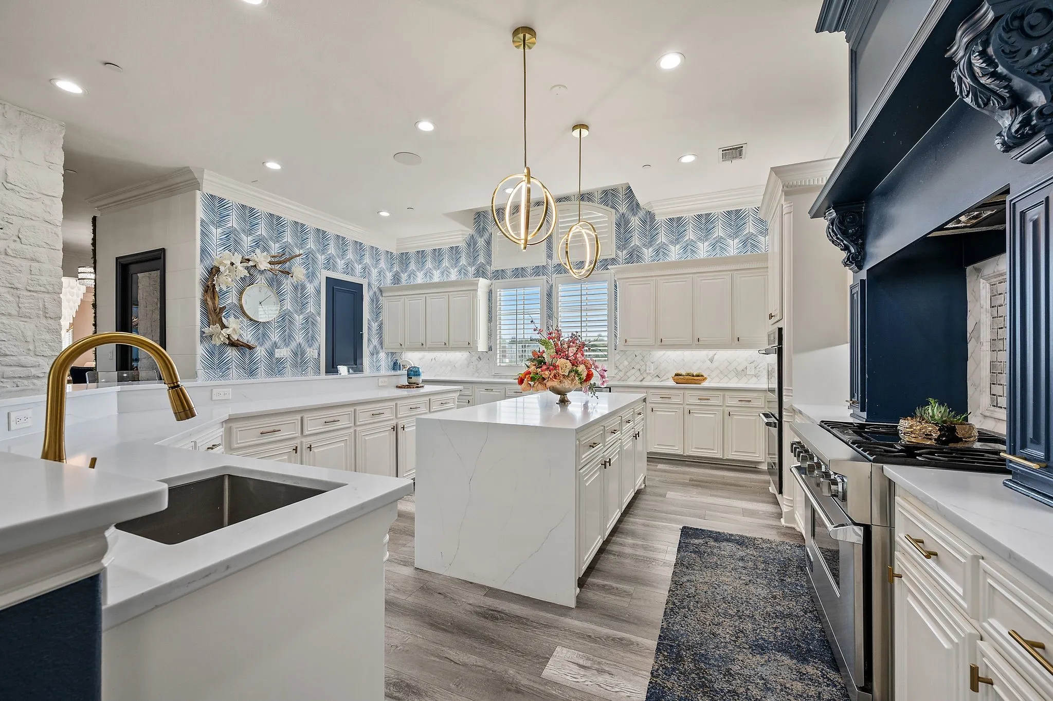 Expansive kitchen featuring a large central island, white cabinetry, integrated stainless steel appliances, and wood-finish flooring
