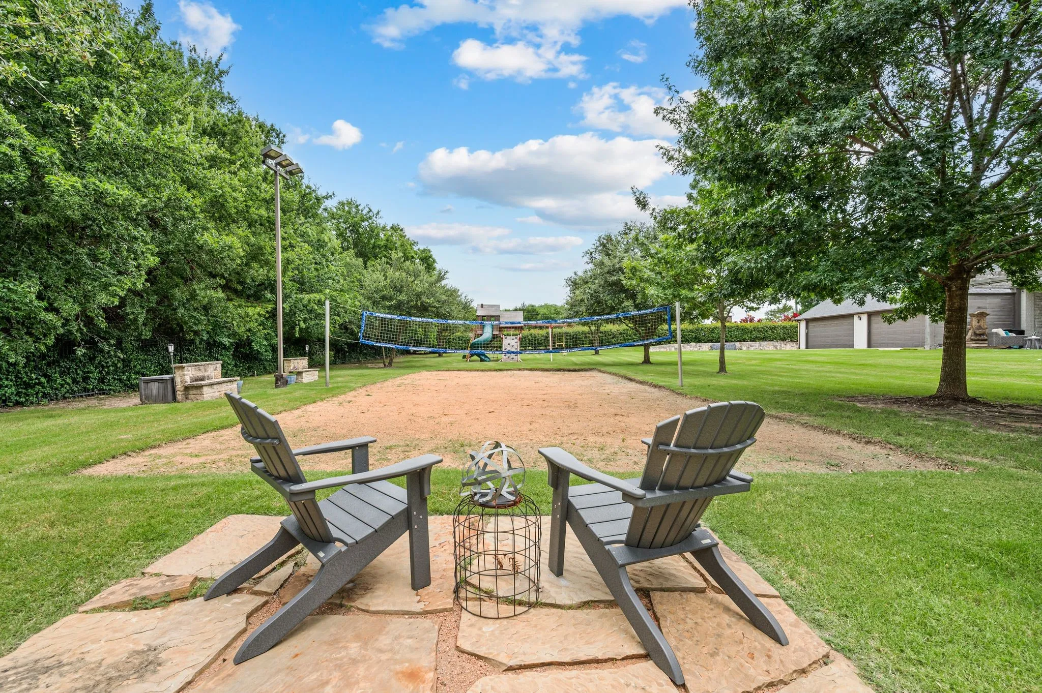 Sand Volleyball Court  surrounded by mature trees and manicured lawn