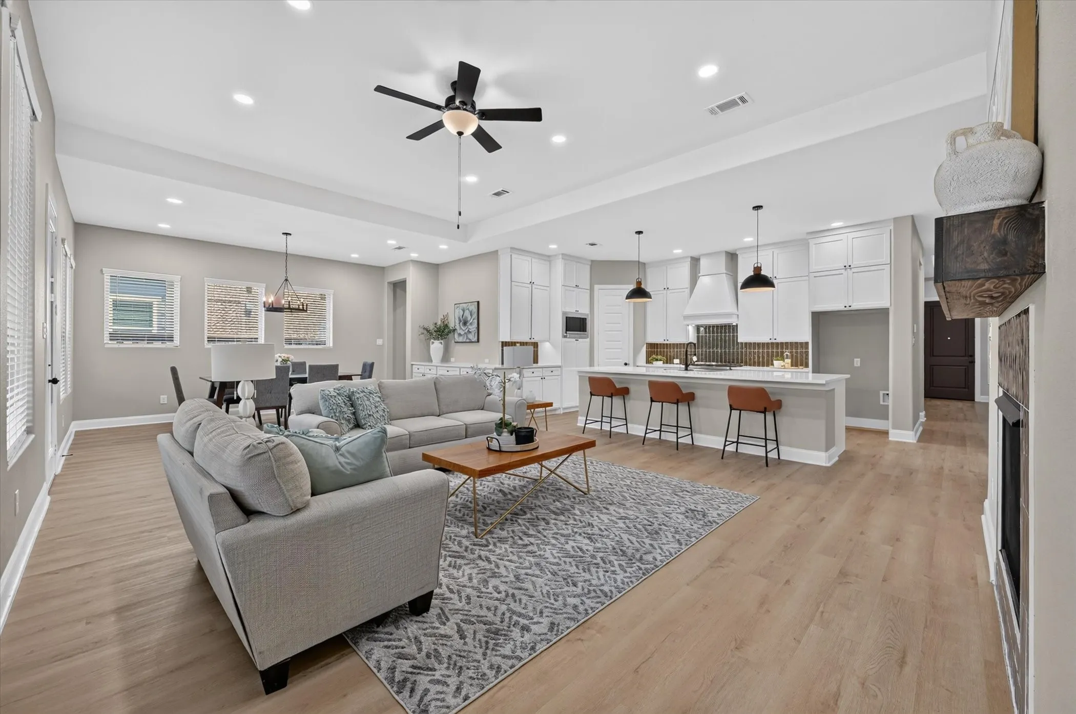Open-concept living space featuring wood-finish flooring, recessed lighting, and a tray ceiling