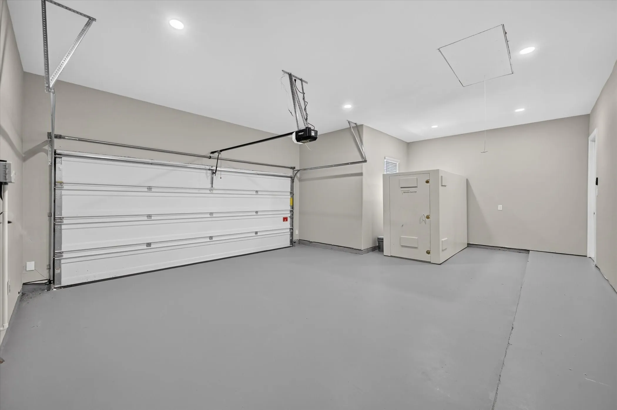 Spacious garage featuring a sectional garage door, painted floor, recessed lighting, and access panel