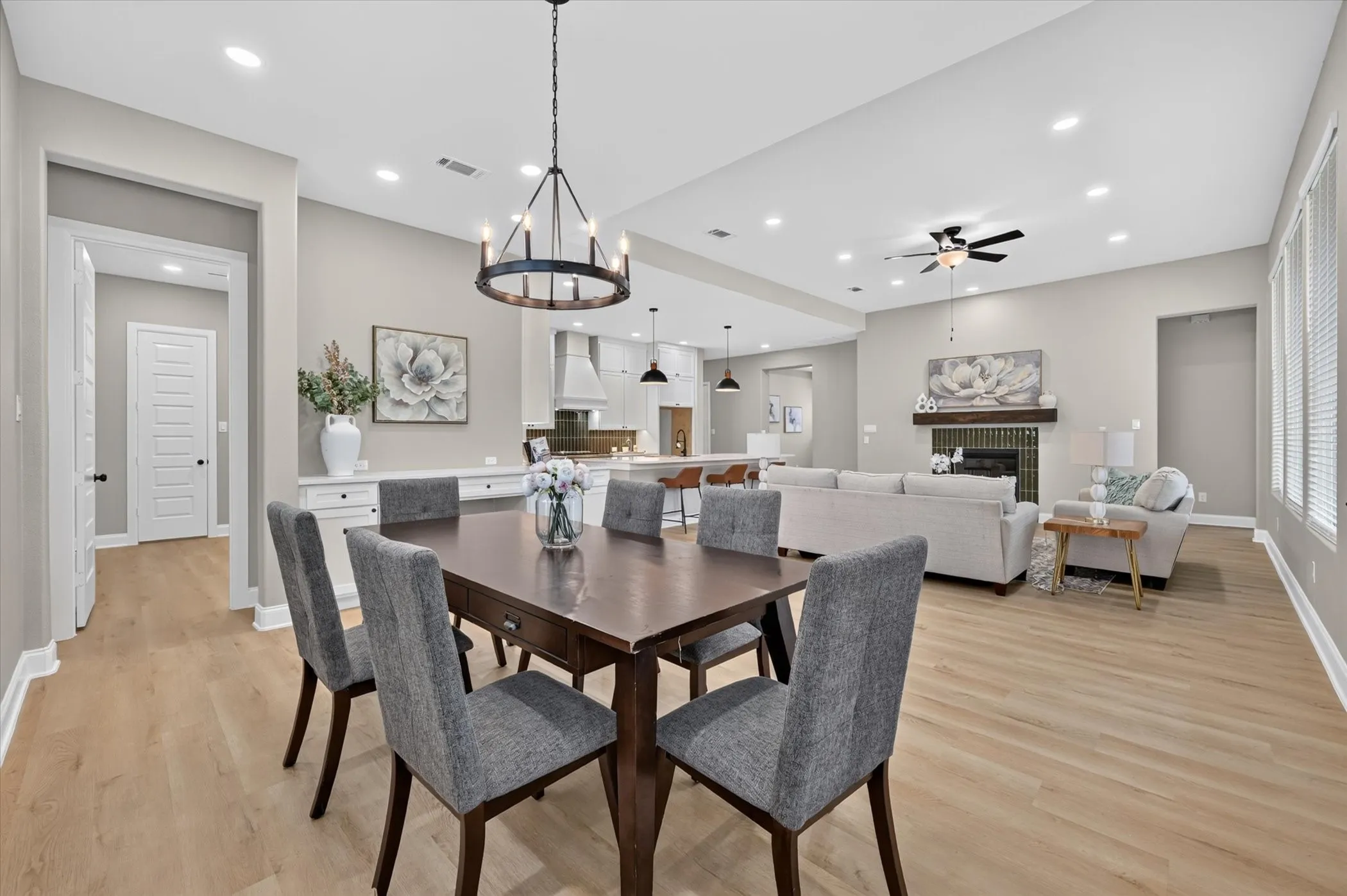 Open-concept living area featuring wood-finish flooring, recessed lighting, and a prominent fireplace with a wood mantle