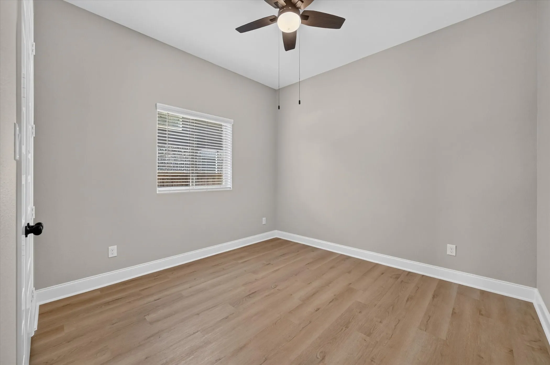 Neutral wall paint, wood-finish flooring, window with blinds, ceiling fan with integrated lighting, and white trim
