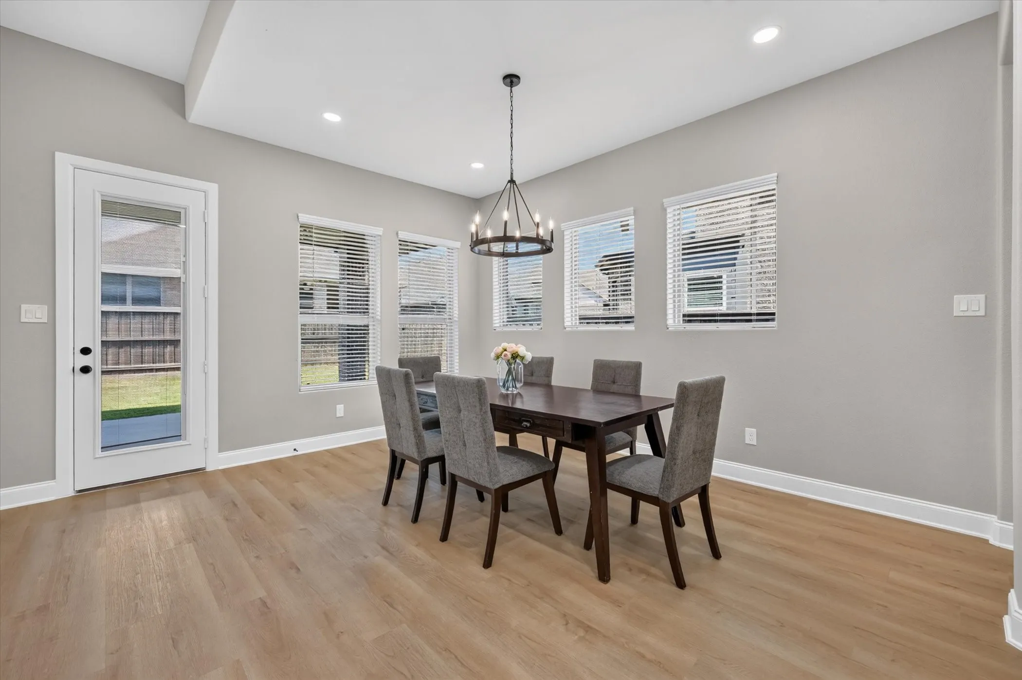 Wood-finish flooring, recessed lighting, white trim, multiple windows, and a glass-paneled door