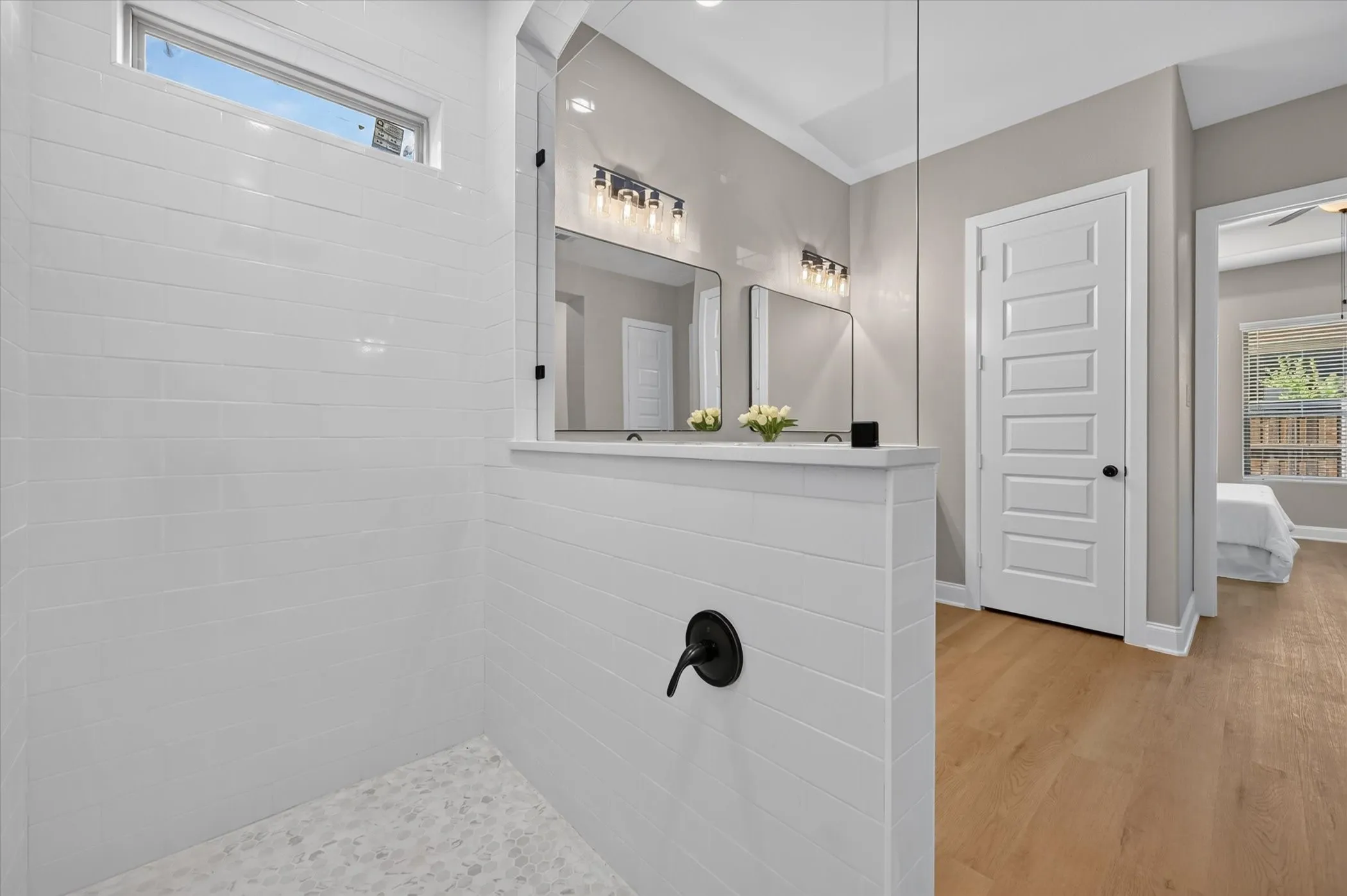 Walk-in shower with white subway tile, pebble tile floor, and transom window