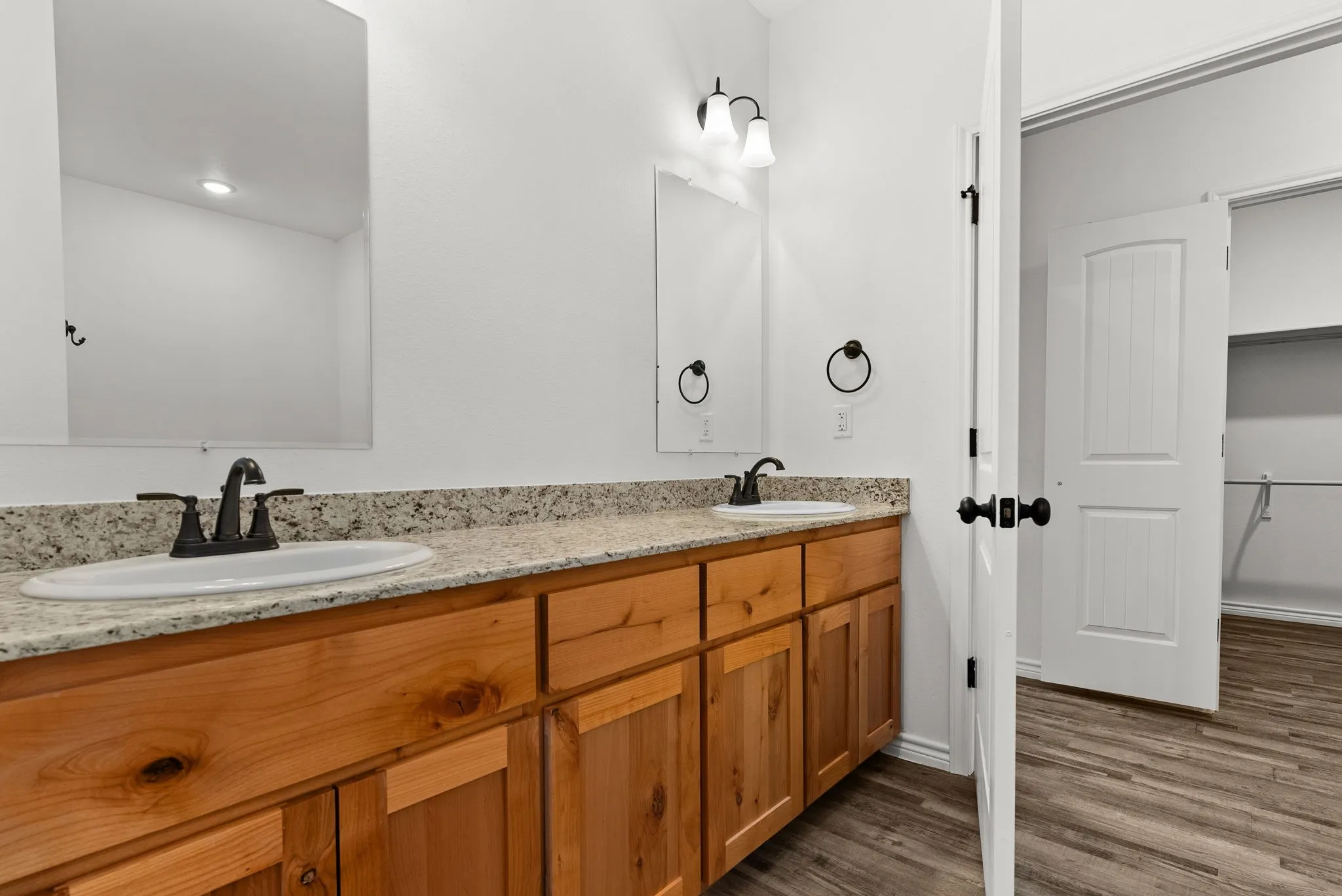 Dual vanity with light-toned countertop, wood-finish cabinetry, and matte black fixtures