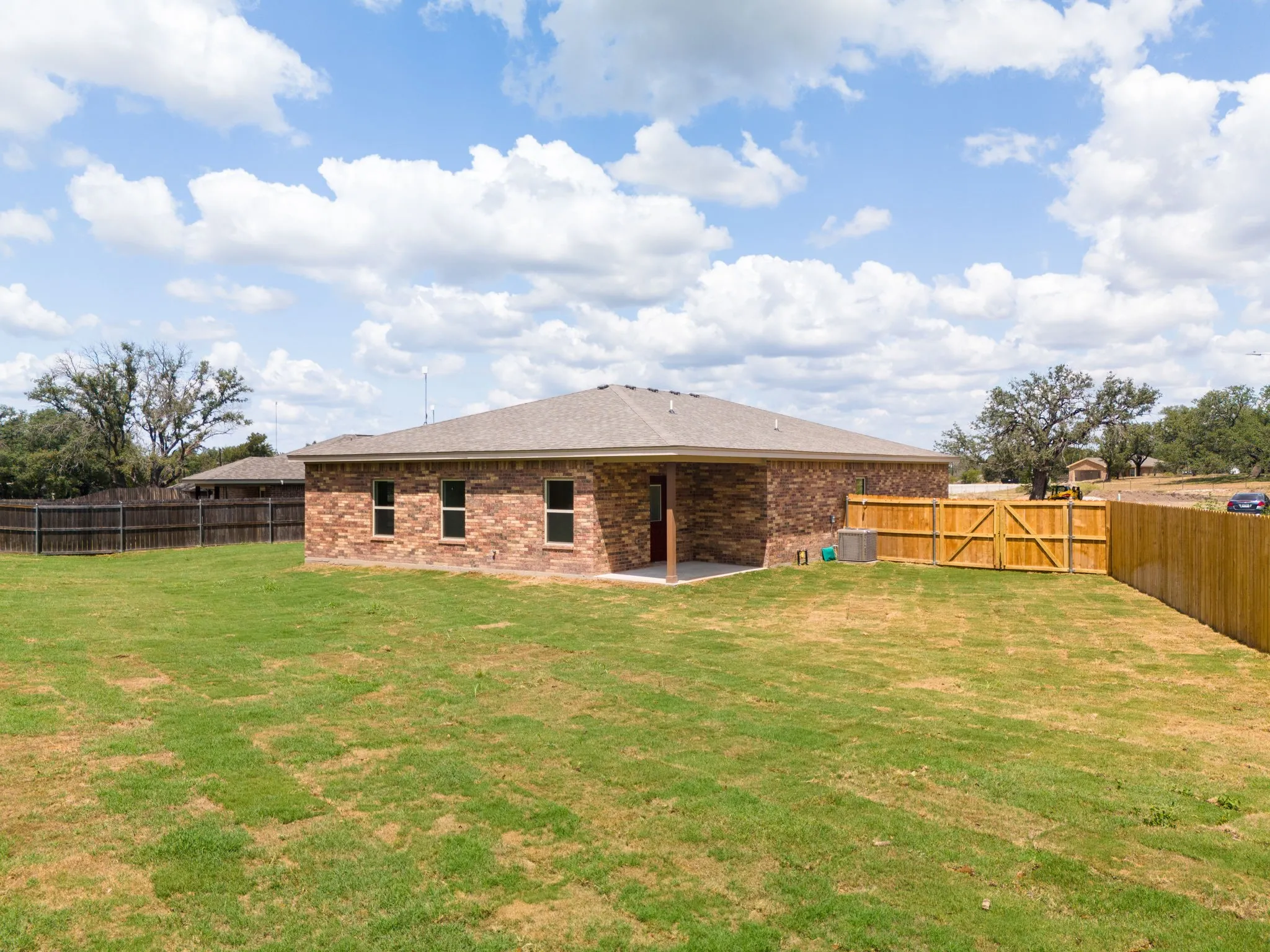 Brick exterior featuring multiple windows and a covered patio