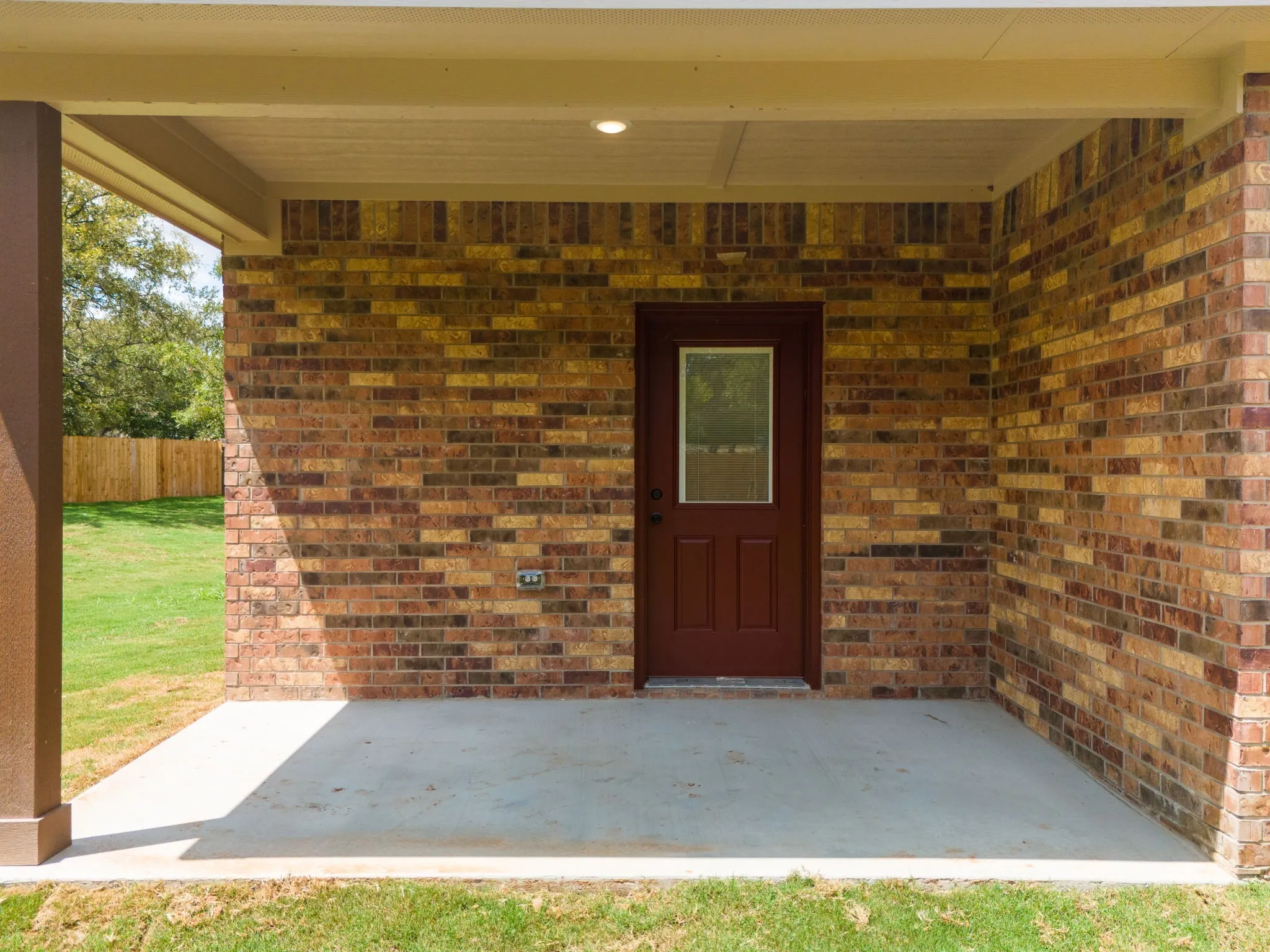 Covered patio featuring a solid brick wall and a wood-paneled door with a glass insert