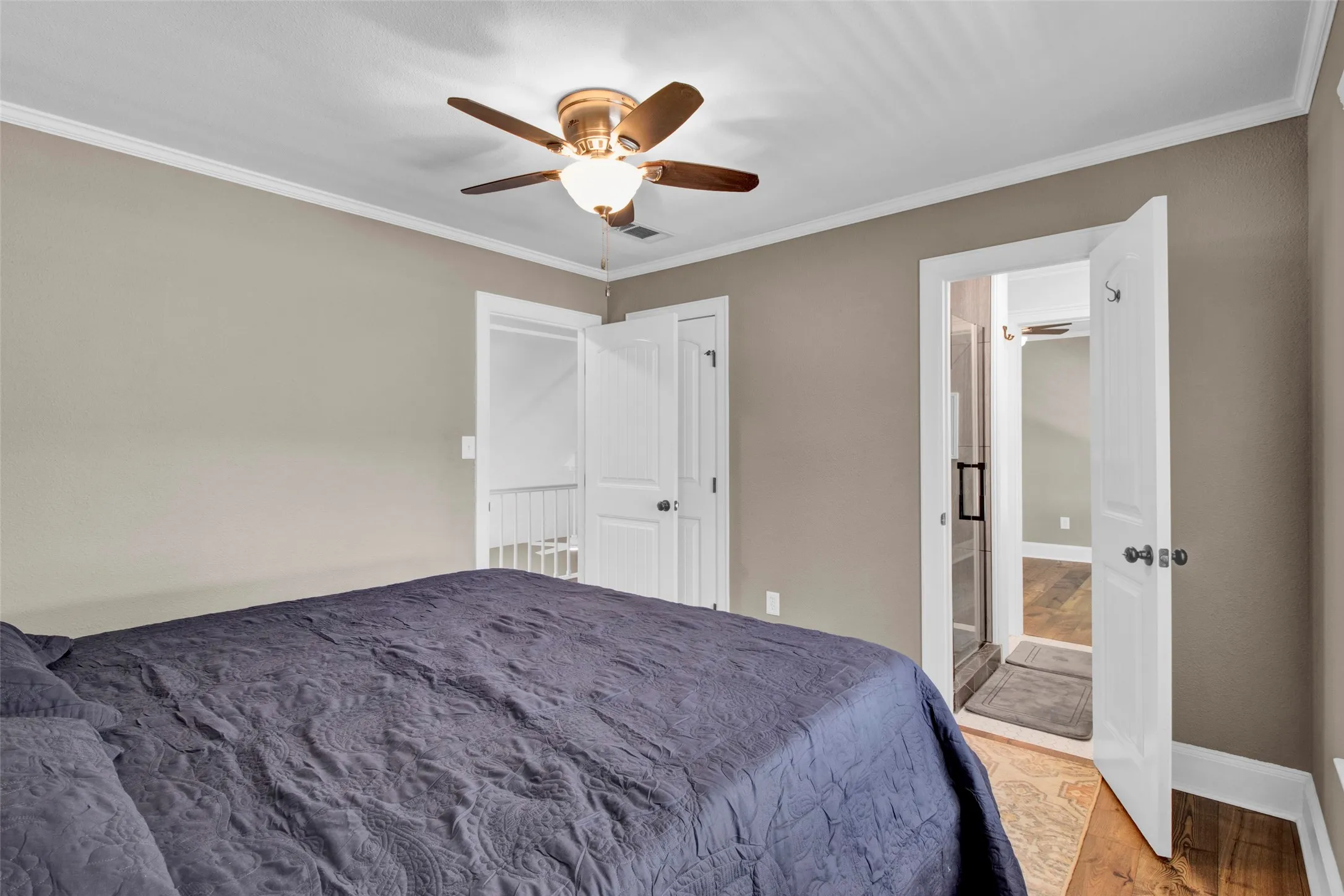 Ceiling fan with integrated lighting, crown molding, white trim, wood-finish flooring, and a glass-enclosed shower
