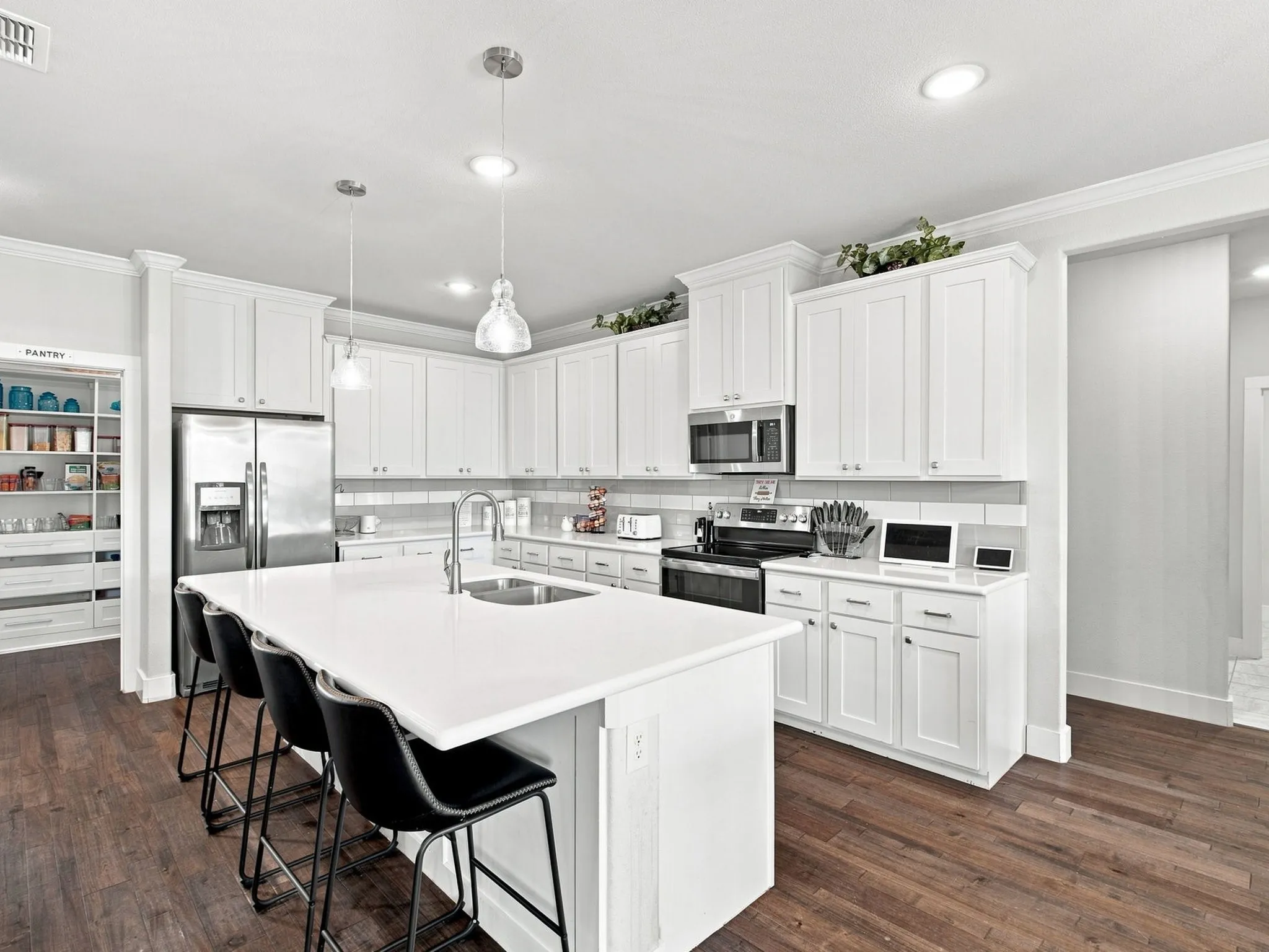 Bright kitchen featuring white cabinetry, stainless steel appliances, a center island with countertop seating, wood-finish flooring, and recessed lighting