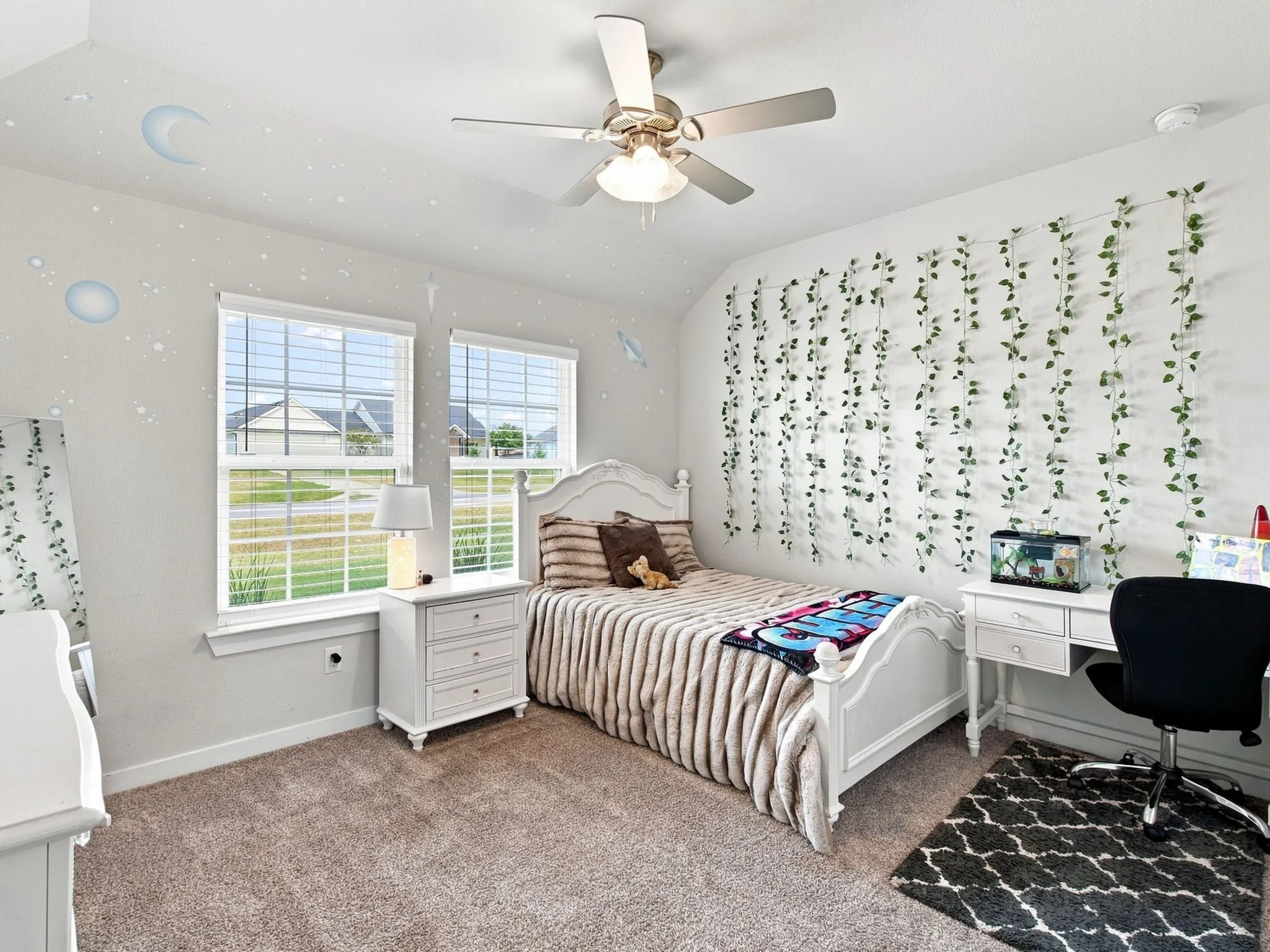 Plush carpet flooring, dual windows with blinds, a ceiling fan, and white trim
