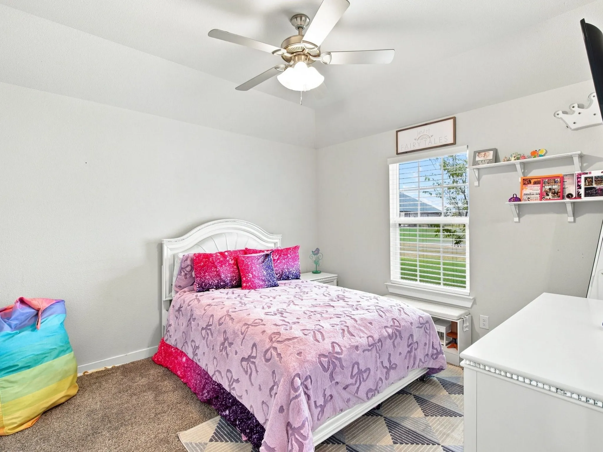 Vaulted ceiling with a ceiling fan, window with horizontal blinds, built-in shelving, and carpeted flooring