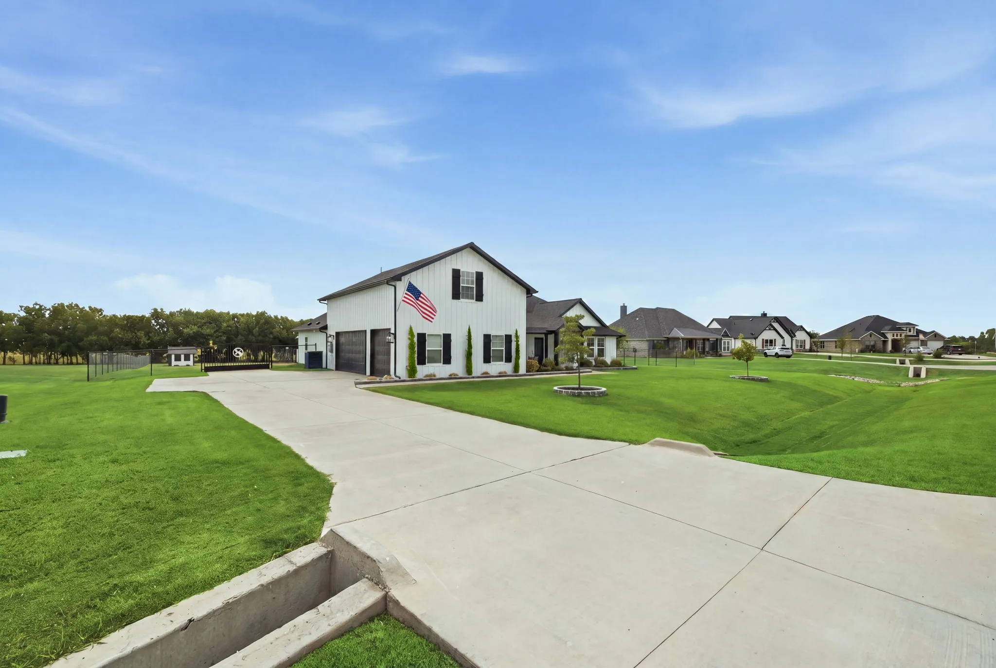 White exterior with black trim, concrete driveway, attached garage, and expansive green lawn - Virtual Grass