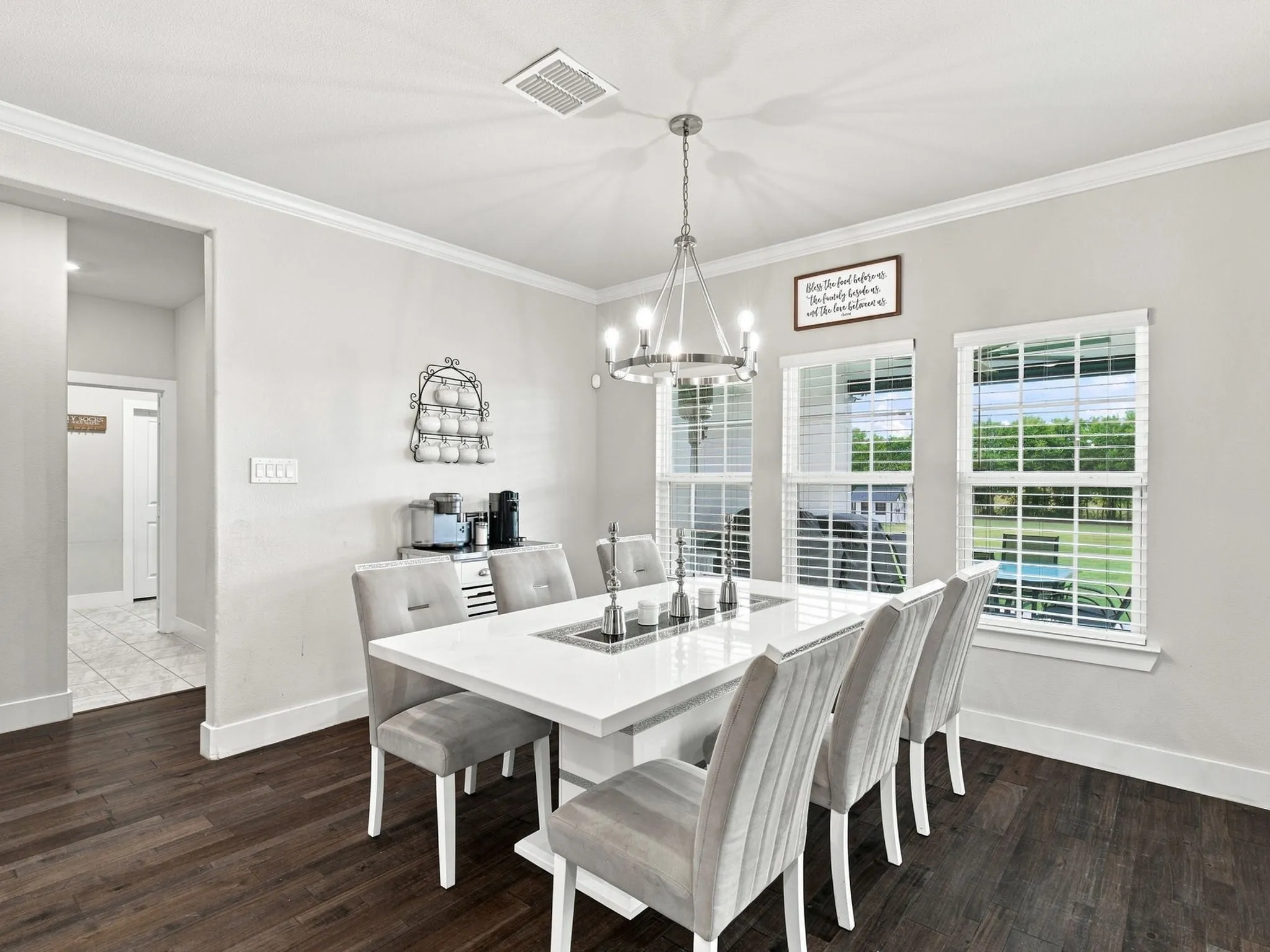 Wood-finish flooring, white crown molding, recessed lighting, and a contemporary chandelier