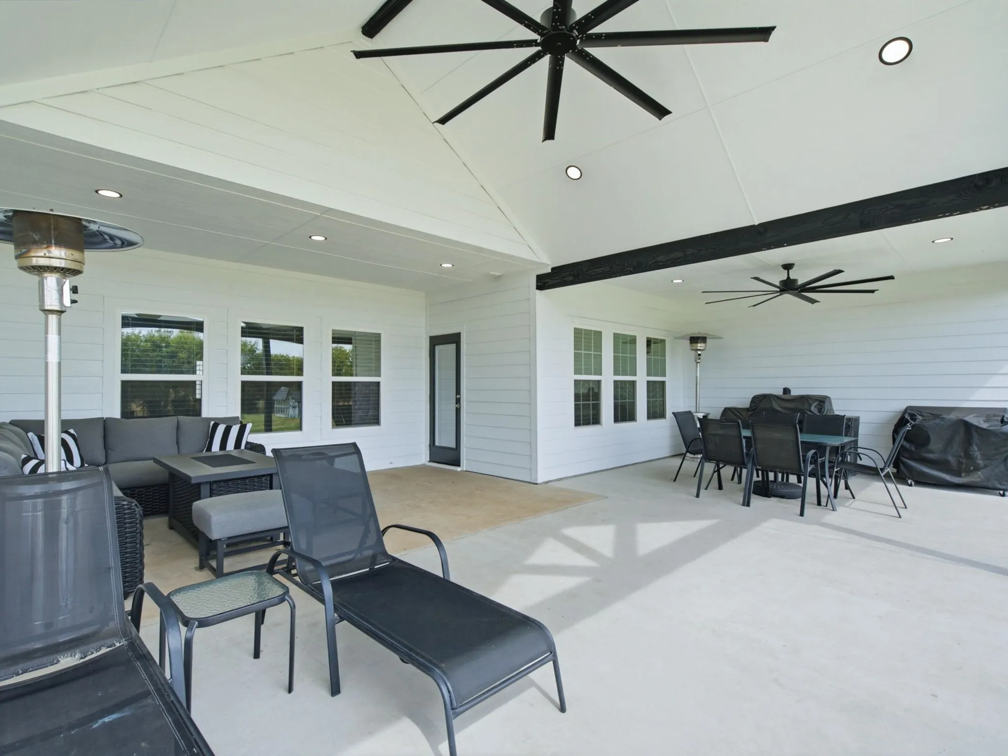 Expansive covered patio with multiple ceiling fans, recessed lighting, and a vaulted ceiling