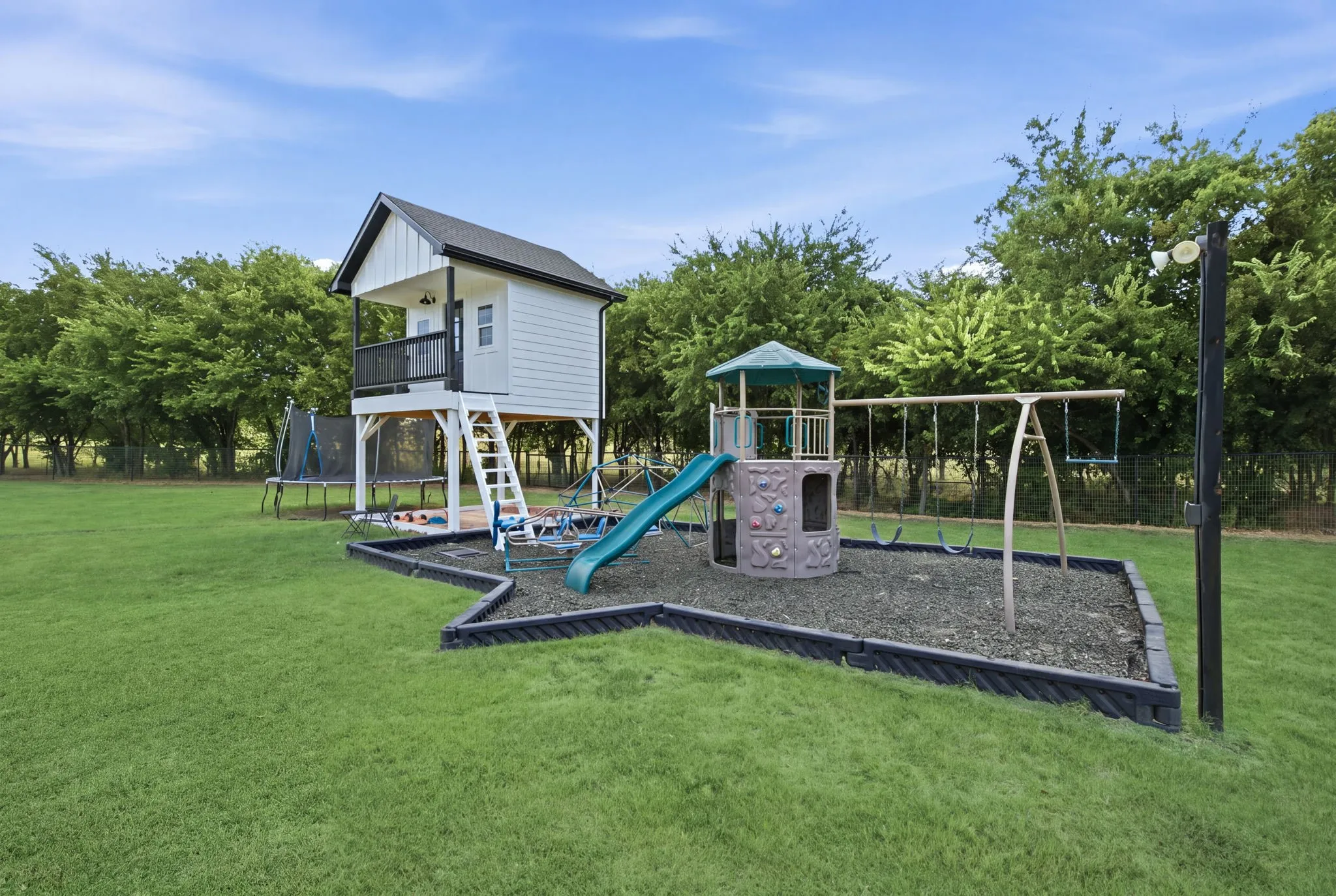 Expansive grass lawn featuring a play structure with a slide and swings, and a raised playhouse with an exterior staircase and porch - Virtual Grass