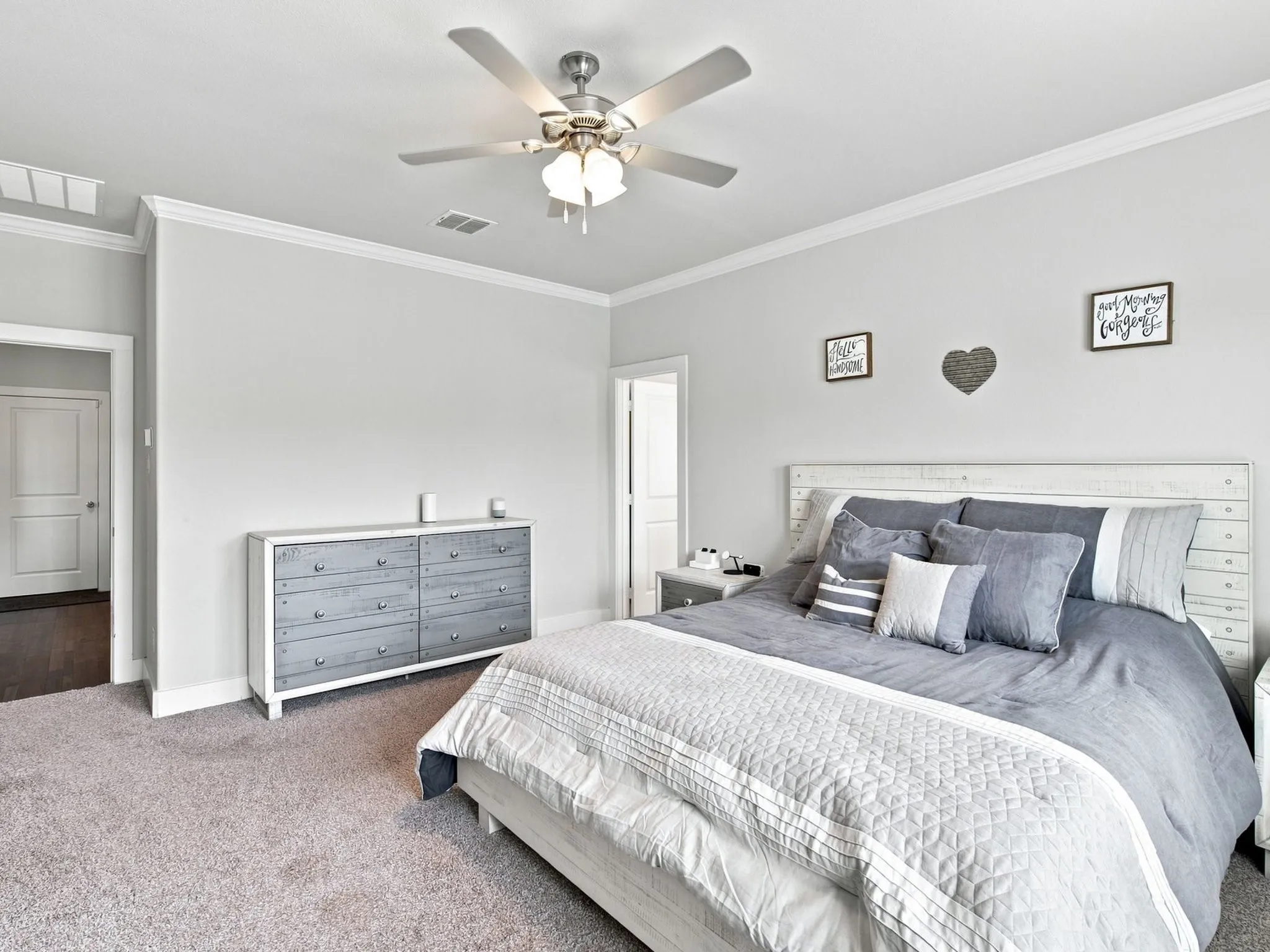 Neutral wall paint, crown molding, ceiling fan with integrated lighting, and soft carpeting