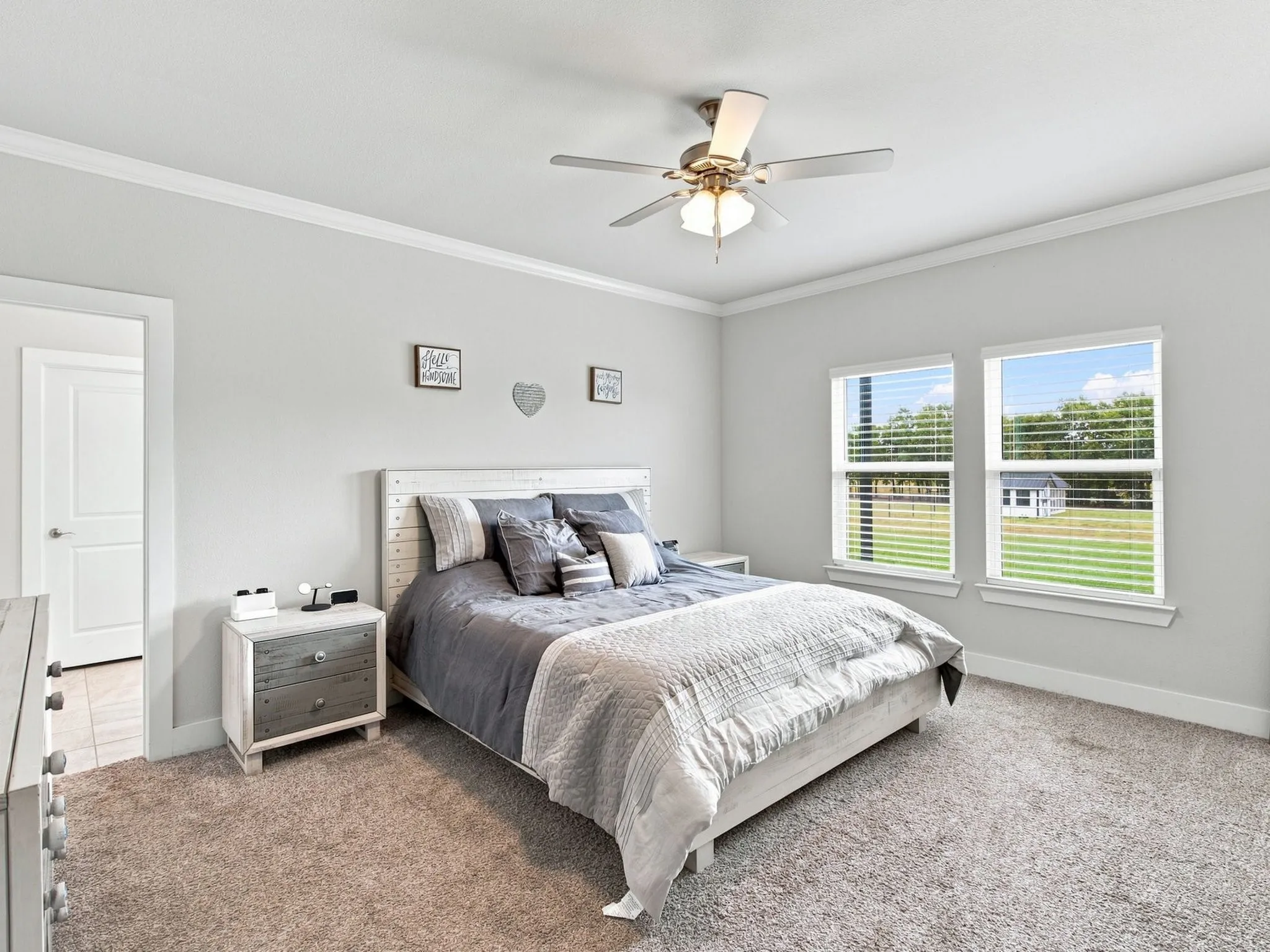 Plush carpeting, two large windows, ceiling fan with integrated lighting, and crown molding