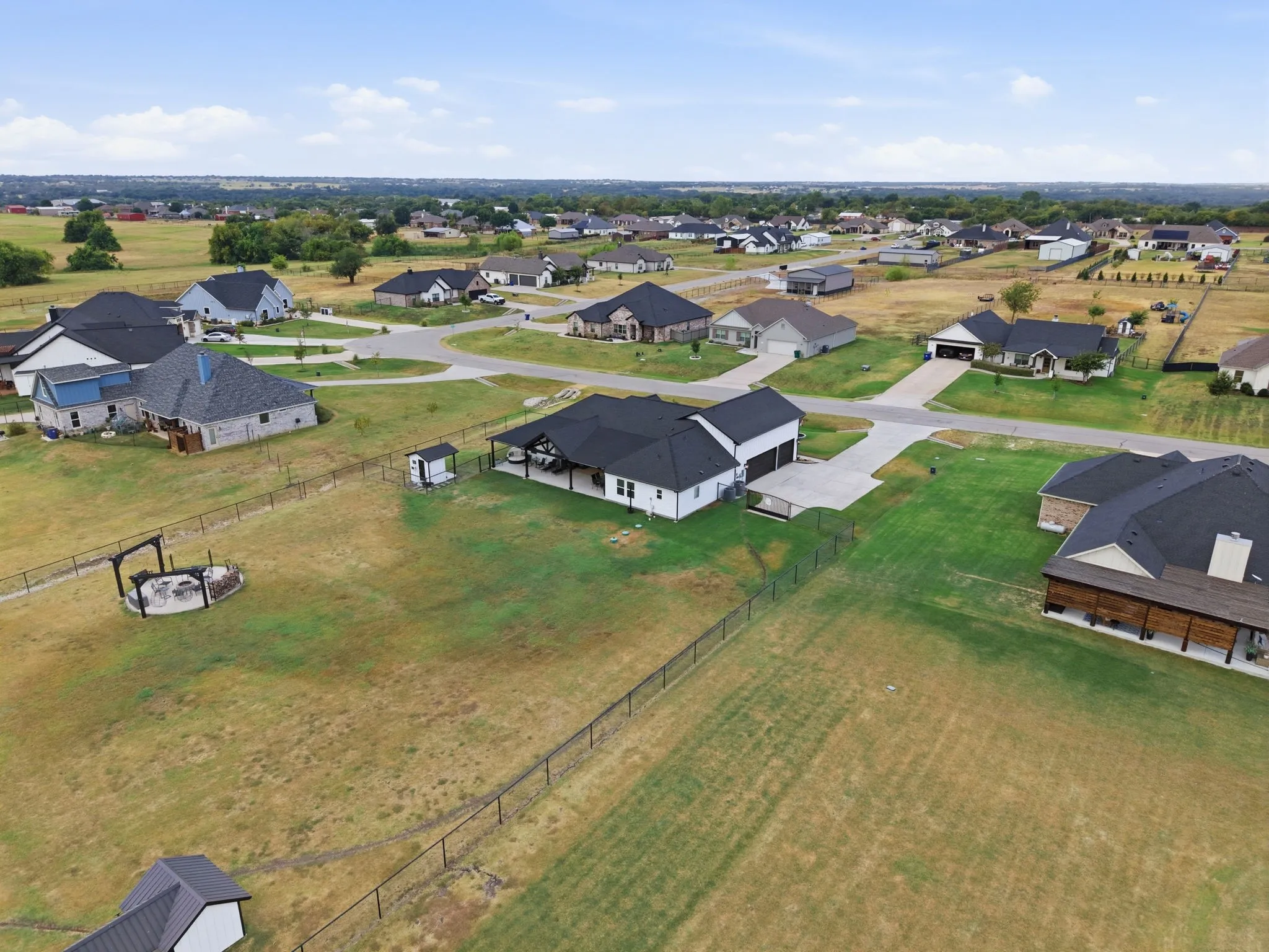 Expansive fenced yard featuring a fire pit area, storage shed, and covered patio