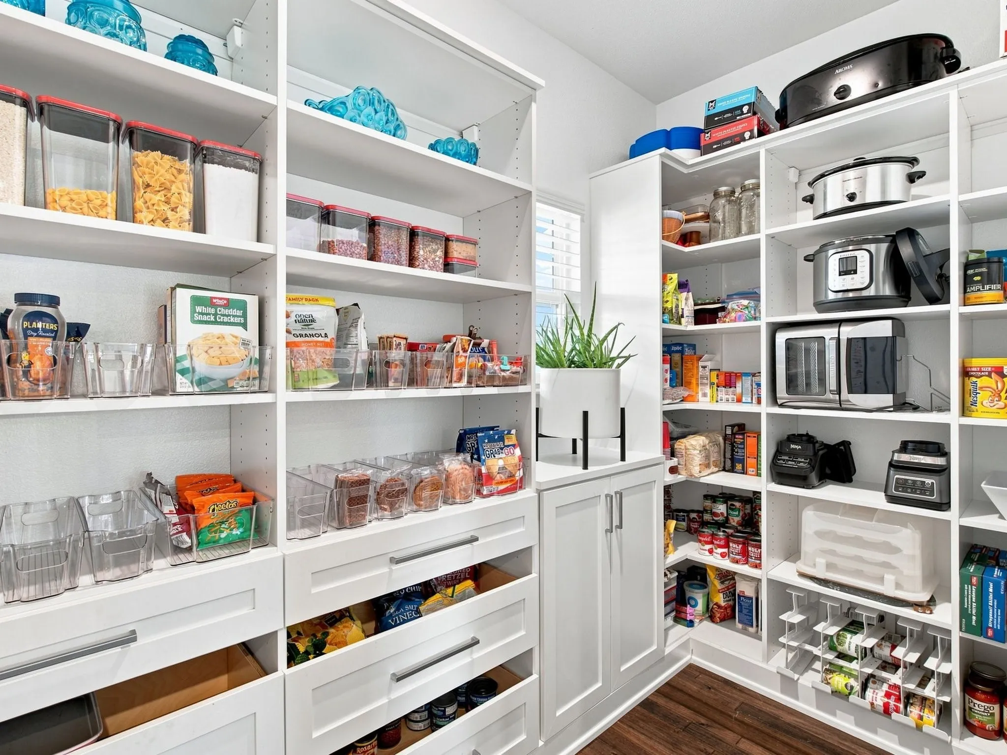 Custom pantry with extensive white shelving, integrated drawers, and a built-in cabinet