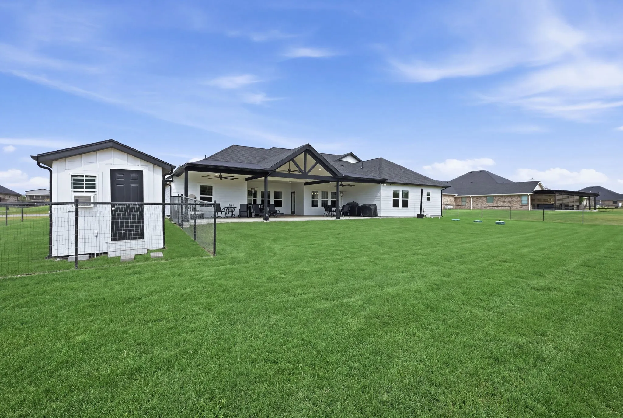 Expansive lawn with perimeter fencing, detached utility shed, and a covered back patio featuring an exposed beam ceiling - Virtual Grass