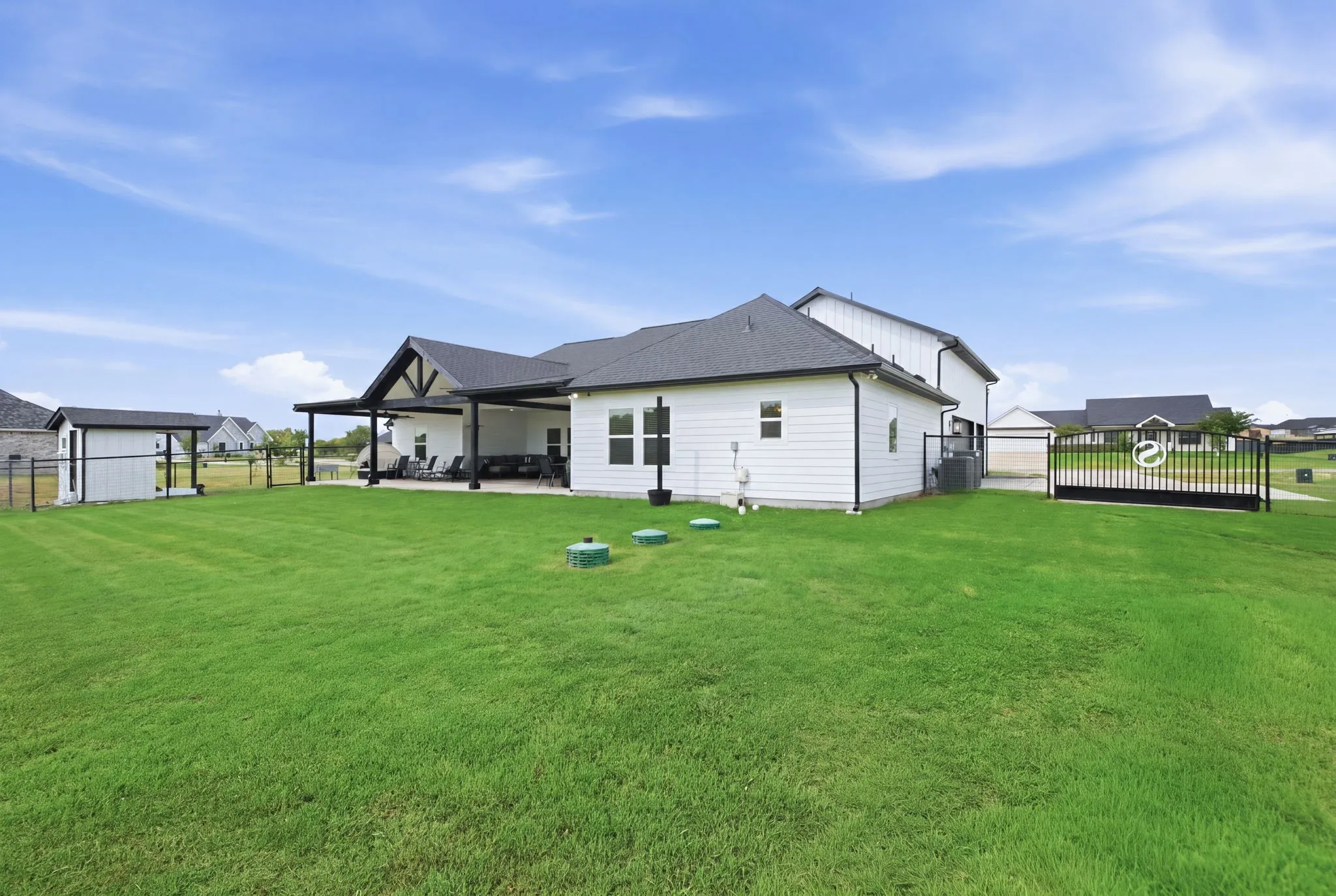 Expansive backyard featuring a manicured lawn, covered patio, and a separate storage shed - Virtual Grass