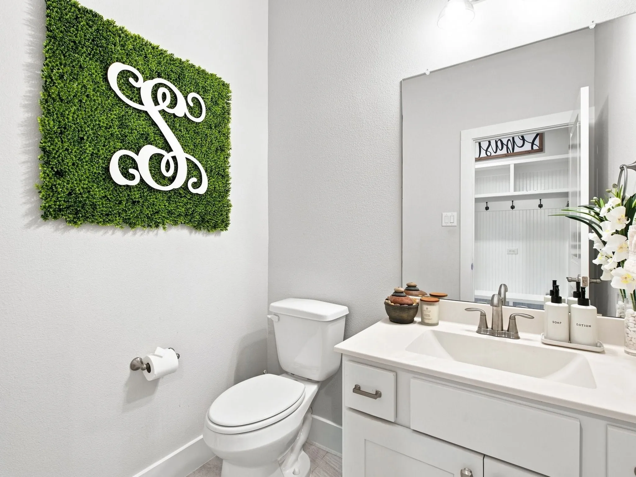 White vanity with an integrated sink and brushed nickel faucet, large wall mirror, and white toilet