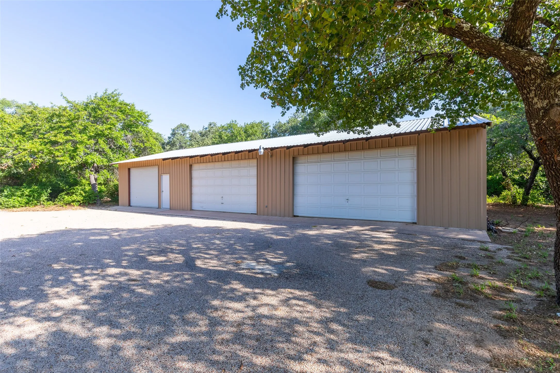 Metal building with a corrugated roof, three roll-up garage doors, and a single pedestrian door